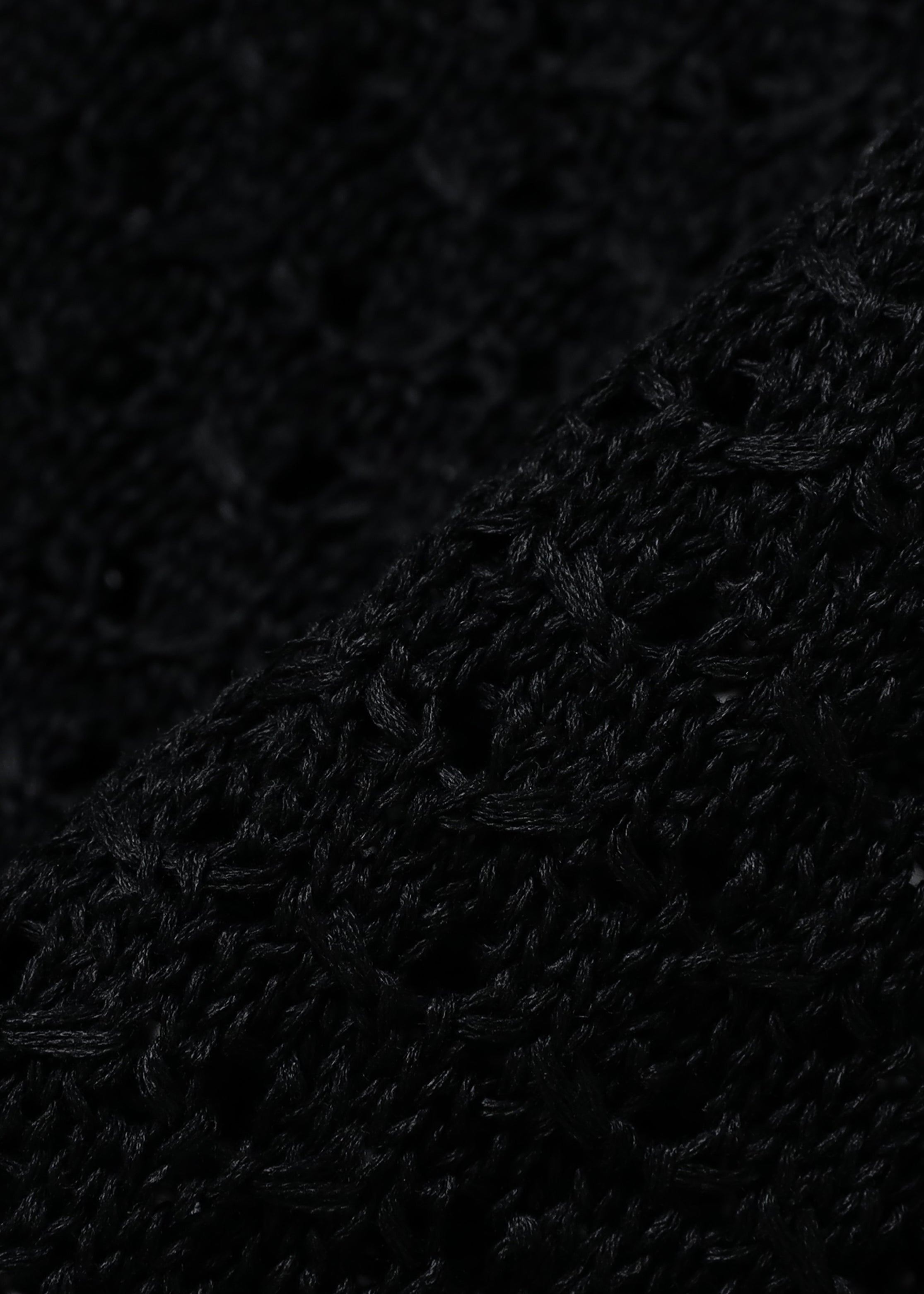 Close up of a black sleeveless mesh knit vest, showcasing the material.