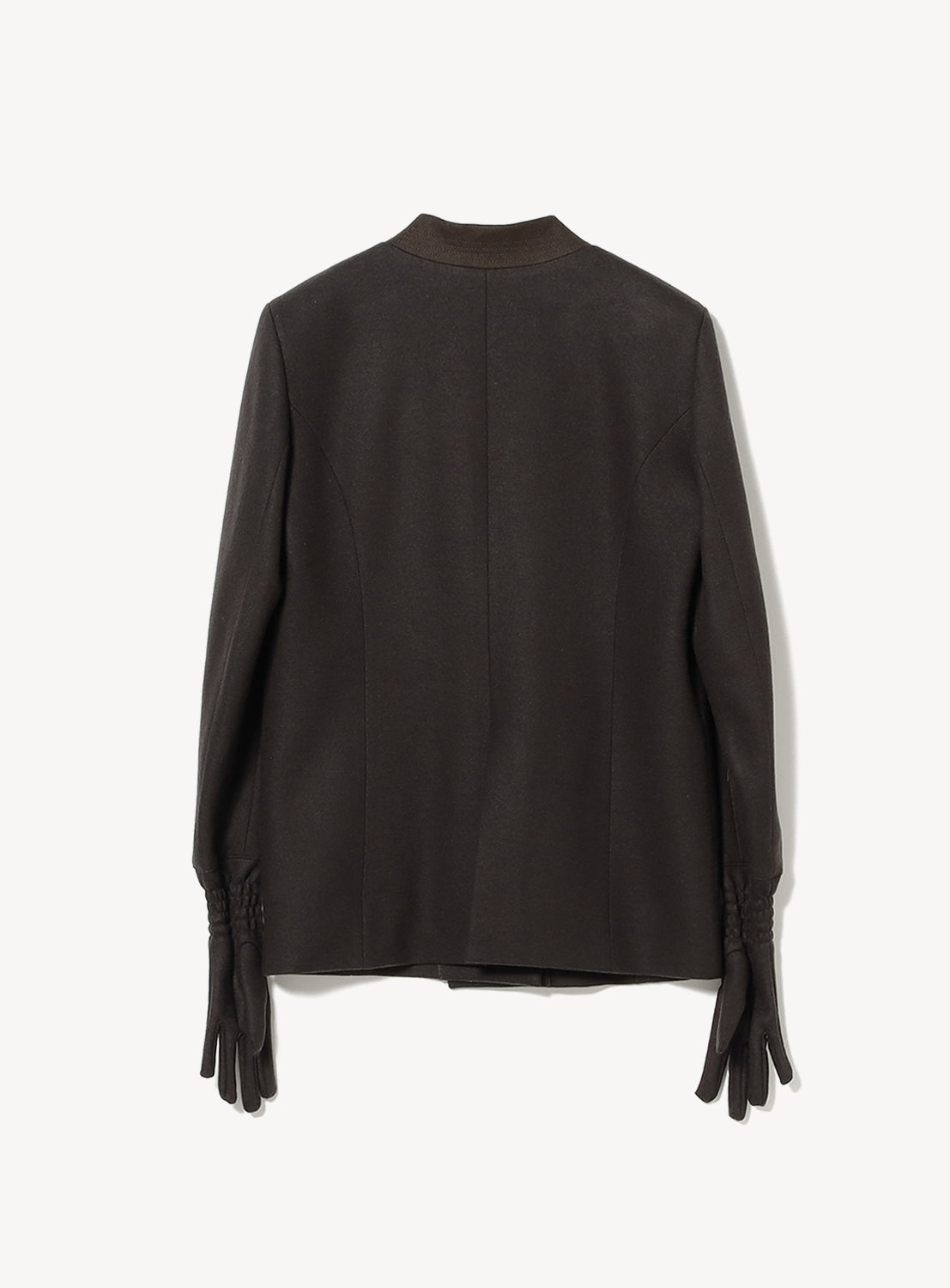 The Anouck Jacket by AKIRANAKA is shown from the back in dark brown, featuring a collarless design and integrated glove sleeves for a unique touch. This tailored piece stands out against a plain white background.