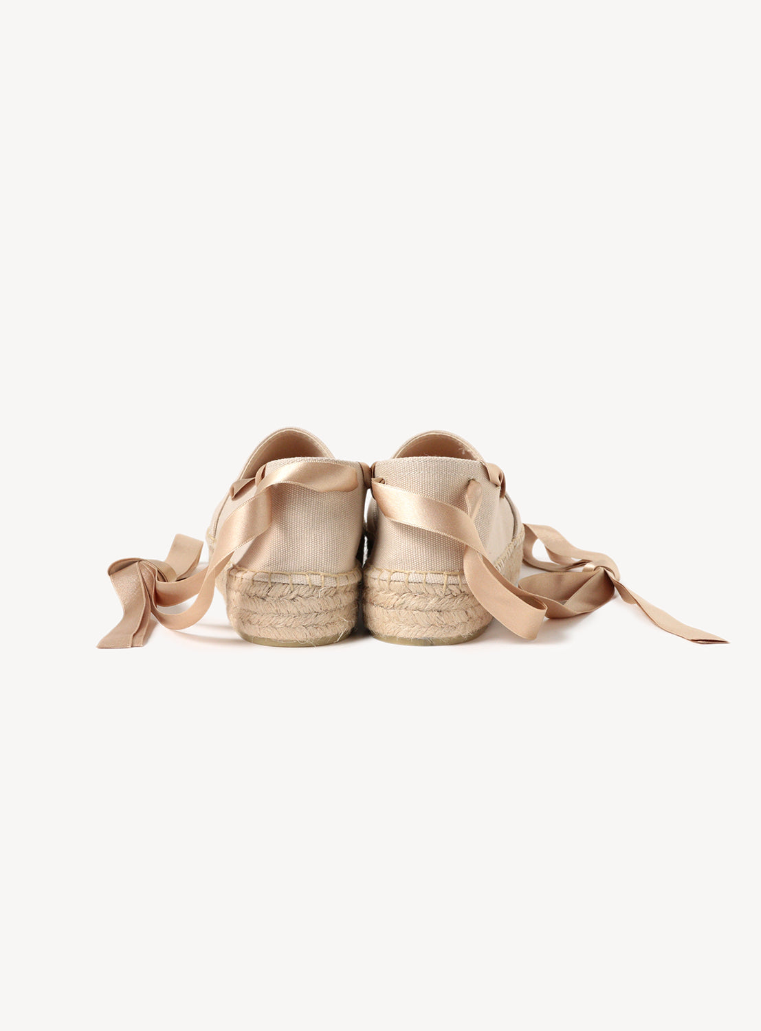 Pair of beige espadrilles with matching satin ribbons.