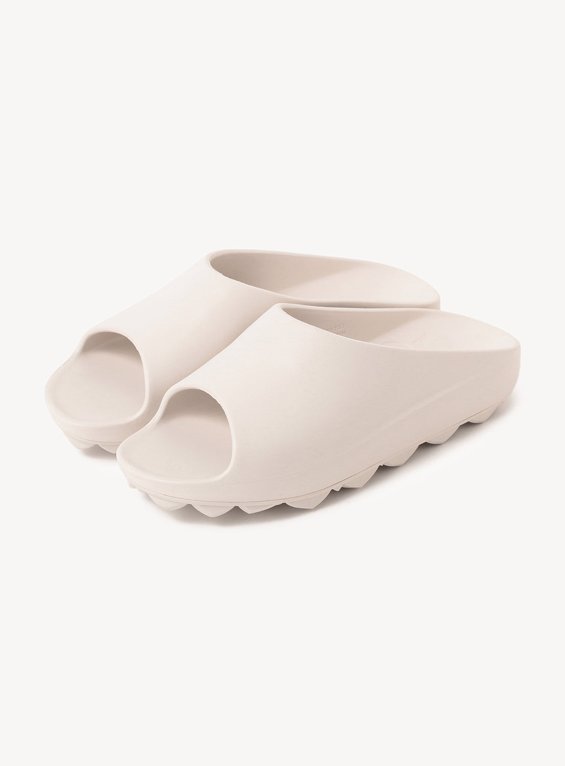 Pair of off-white slip-on slides with a thick, textured sole on.