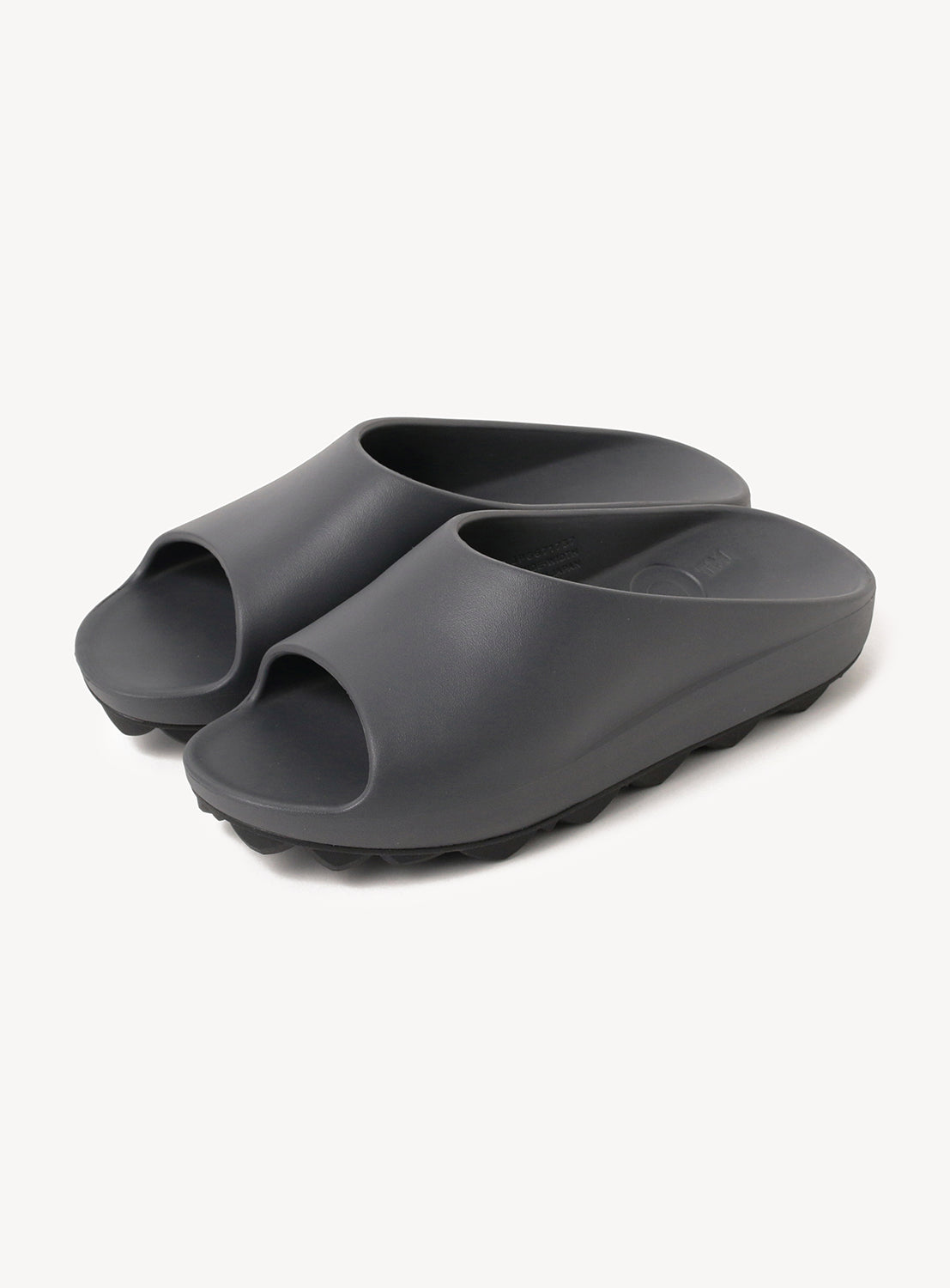 Pair of dark grey slip-on slides with a thick, textured sole.