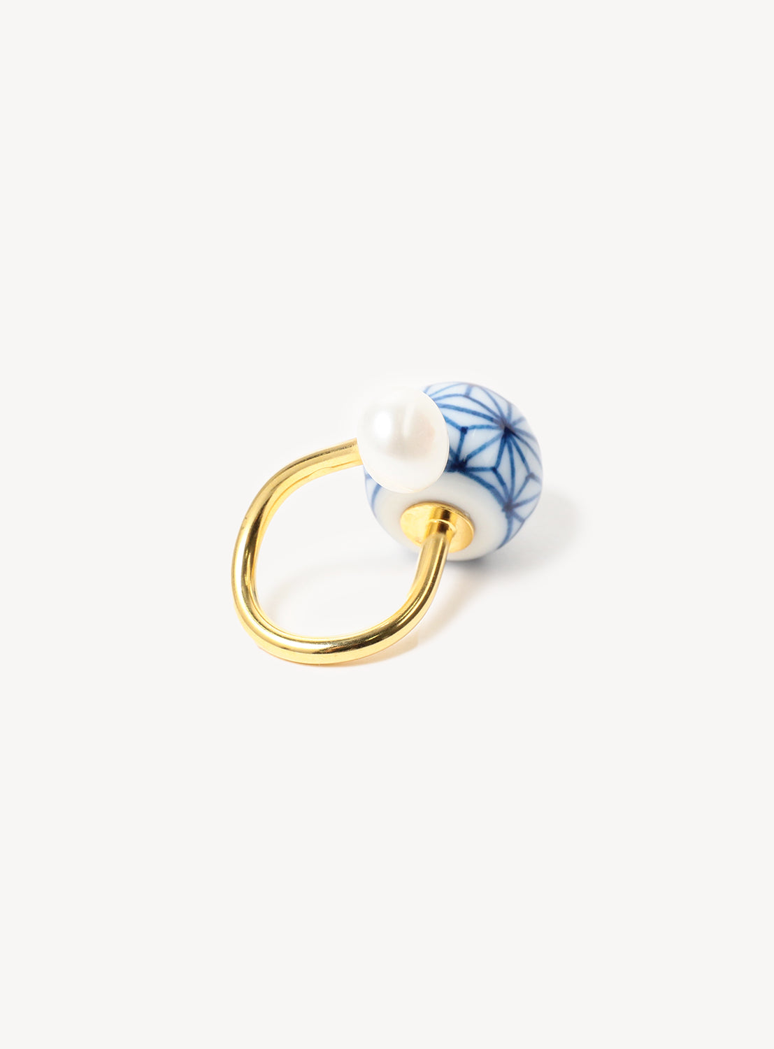 A gold ring with a blue and white geometric patterned motif featuring a freshwater pearl.