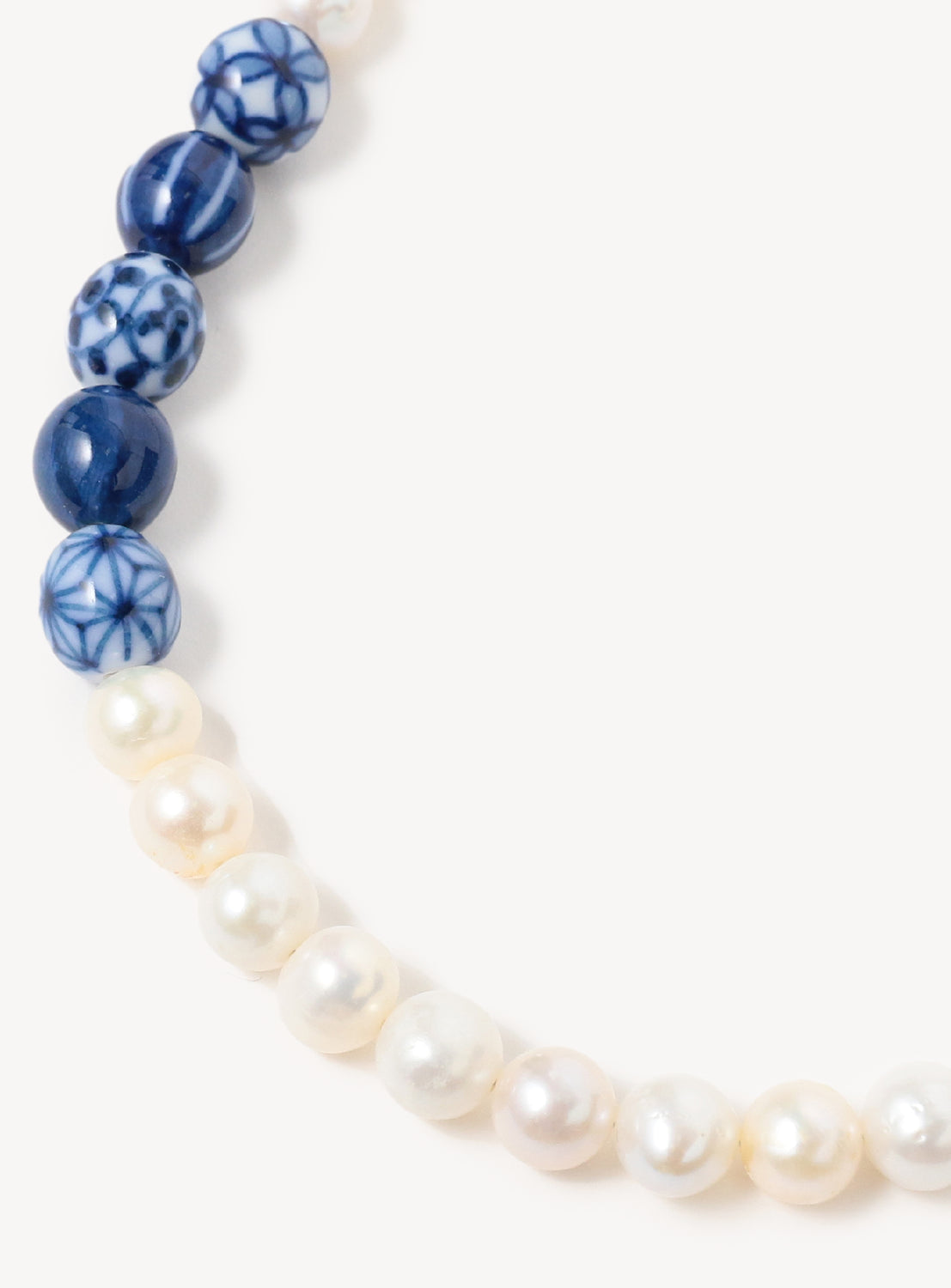 A close up of the pearl beaded necklace with blue ceramic beads.