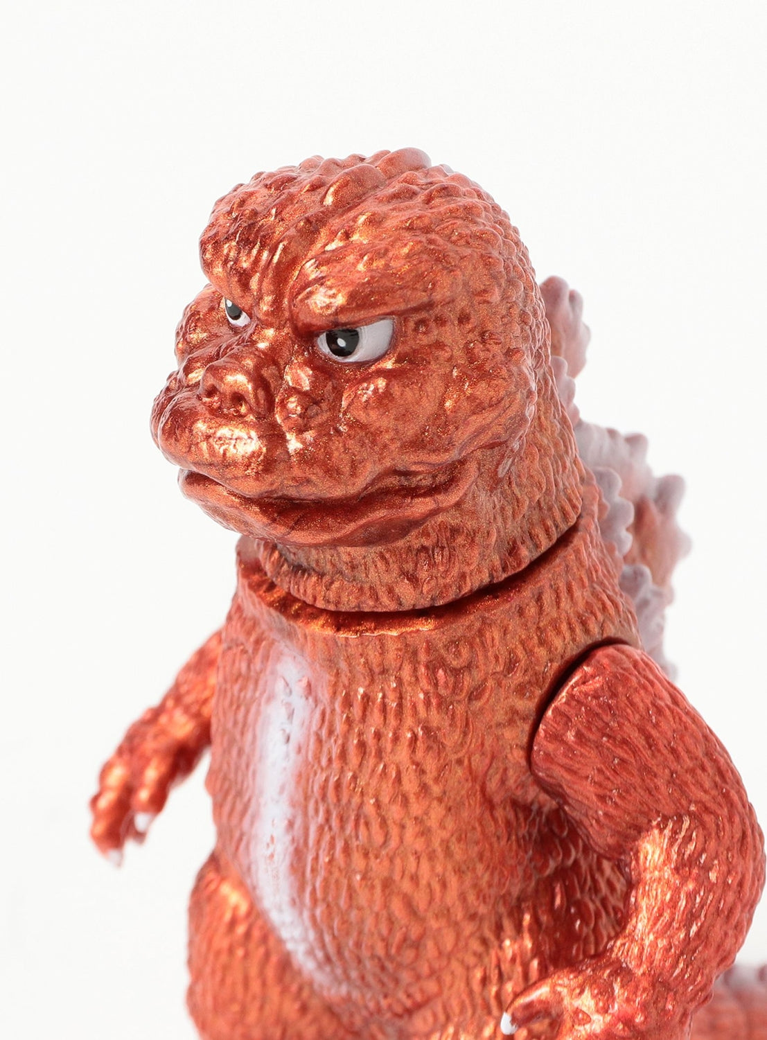 A close-up of a shiny, orange figure from the GODZILLA VINYL ART: Pikopiko's Deformed Godzilla vs. Mechagodzilla (1974) Sofubi Set by TOKYO CULTUART by BEAMS, featuring textured skin and an intense expression against a plain white background—an impressive collectible inspired by sofubi artists and the world of Godzilla vinyl art.