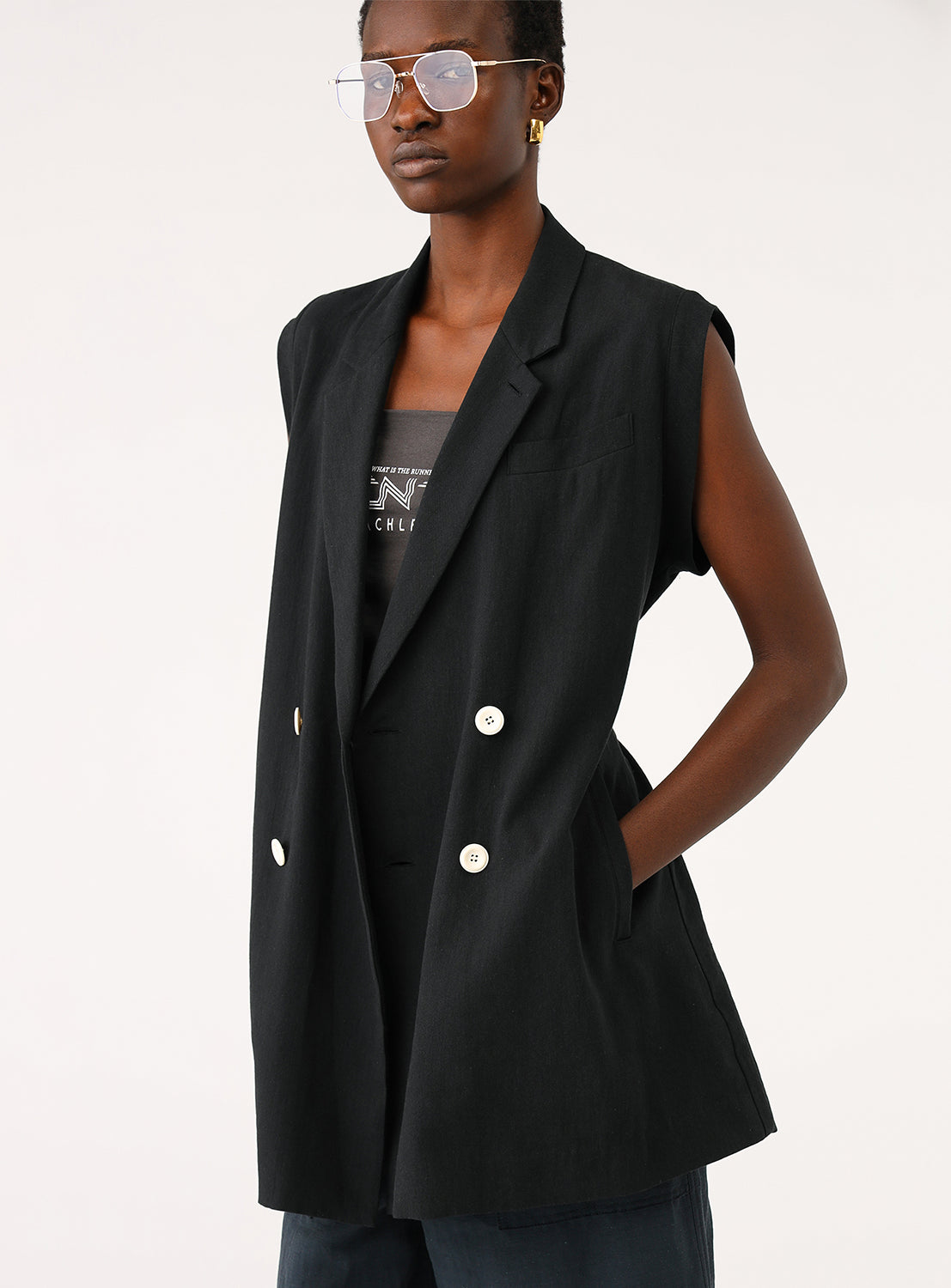 Model wearing a black longline gilet, styled with a casual top and sunglasses.