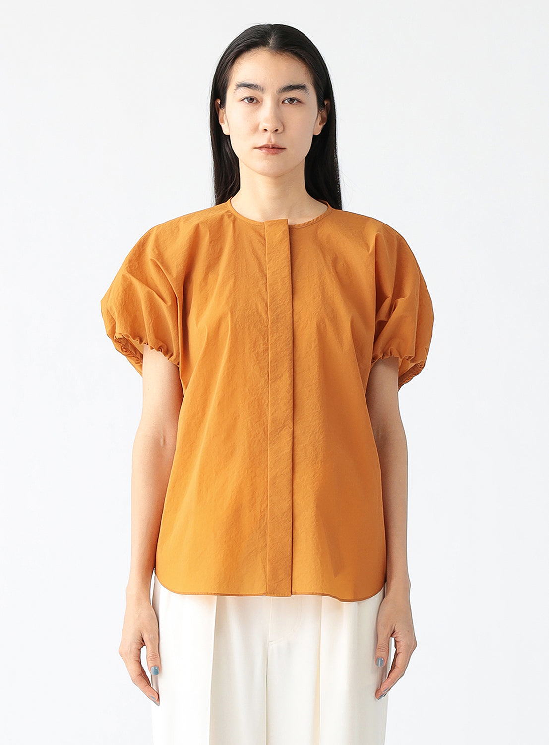 Model wearing a brick blouse, showcasing the voluminous silhouette and softly gathered sleeves.