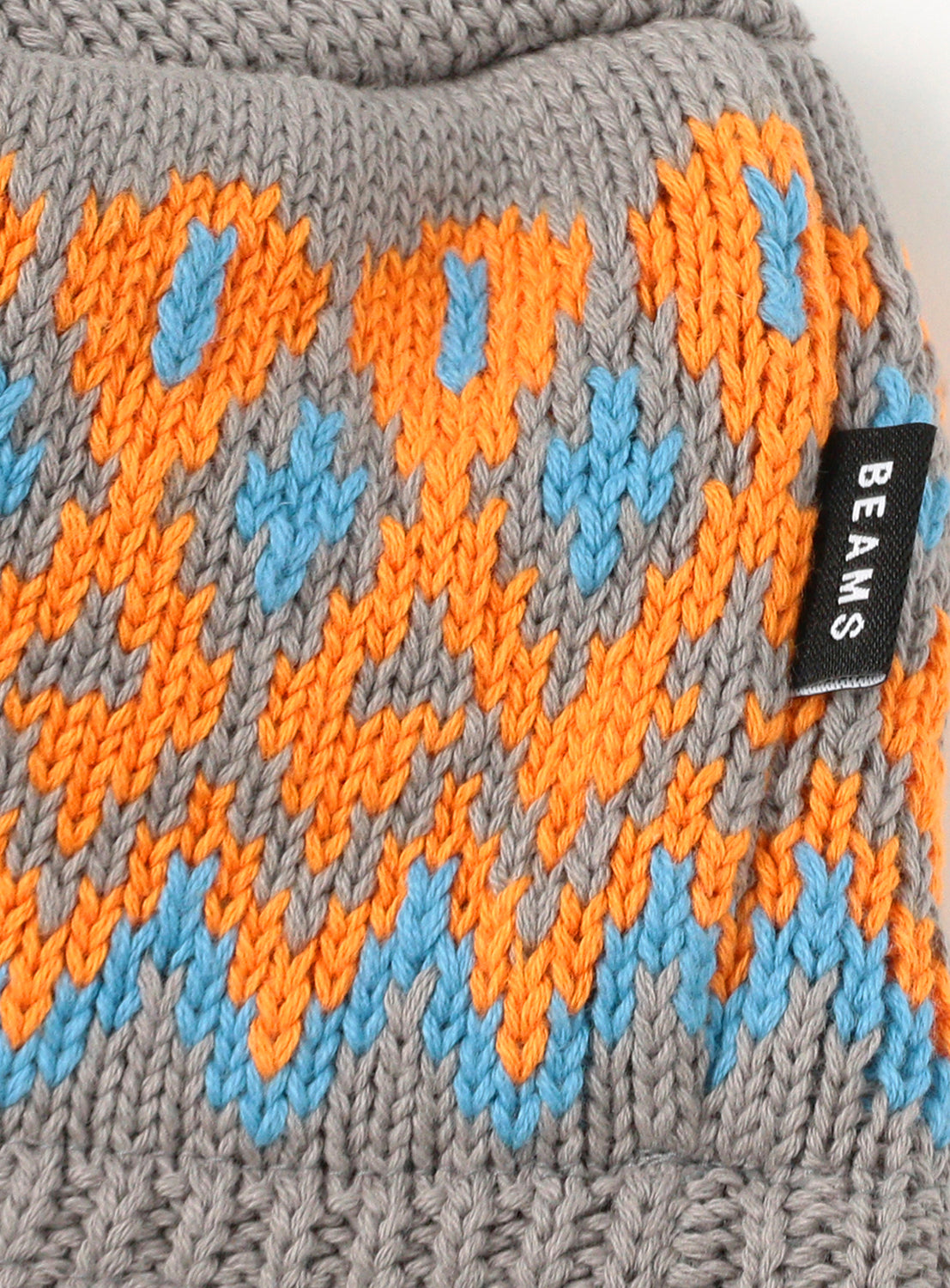 Close up of gray knit beanie with orange and light blue jacquard pattern.