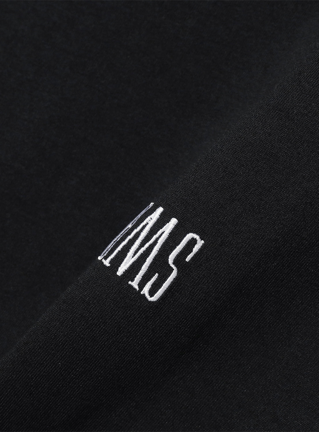 Close-up of the black t-shirt, highlighting the subtle "BMS" embroidery on the left chest.