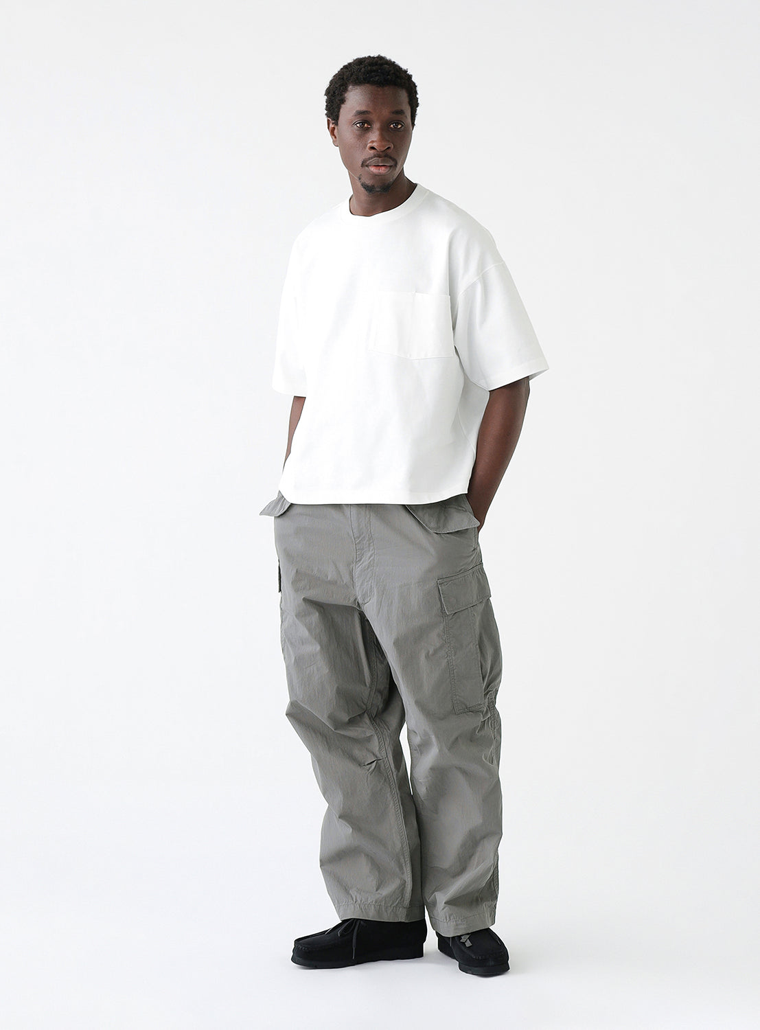 A model wearing a pair of gray cargo pants with multiple pockets, styled.