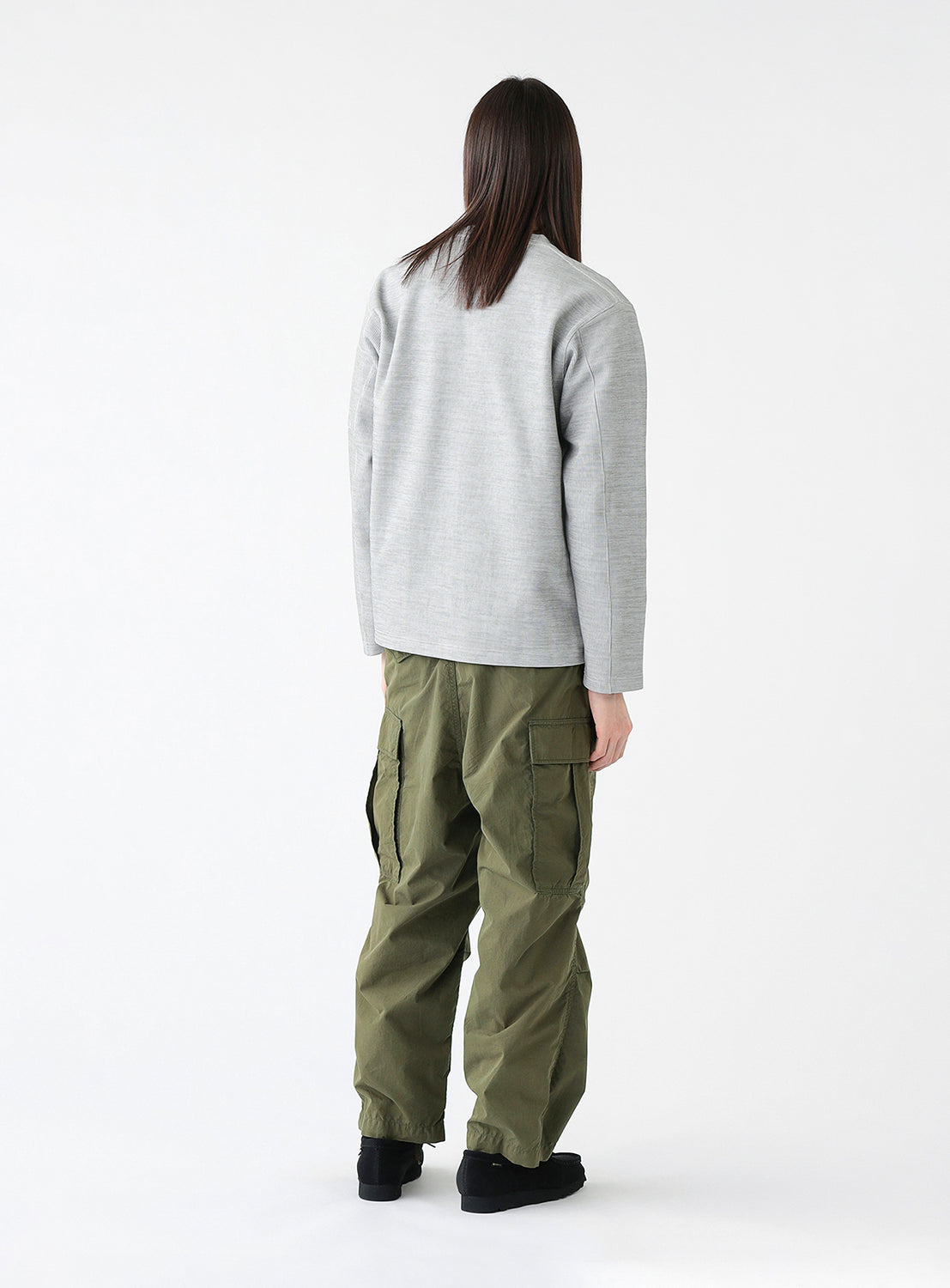 Back view of a model wearing a pair of olive green cargo pants with multiple pockets, styled.