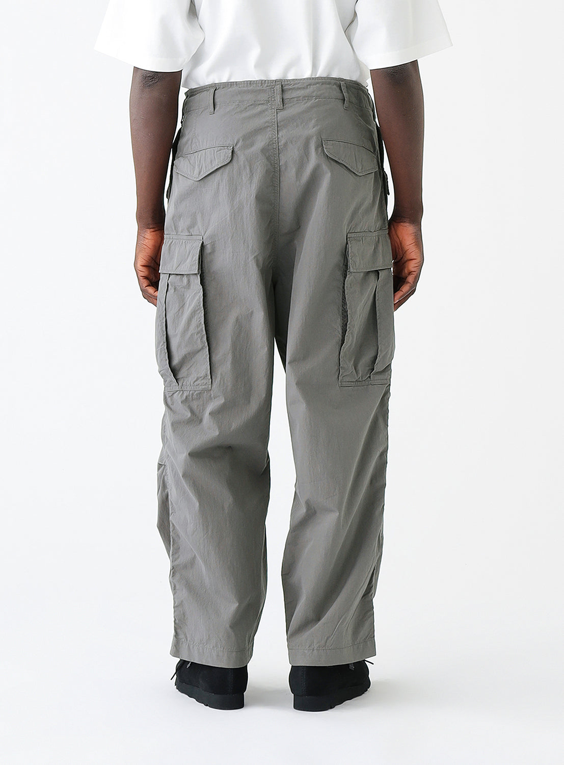Close up back view of model wearing a pair of gray cargo pants with multiple pockets.