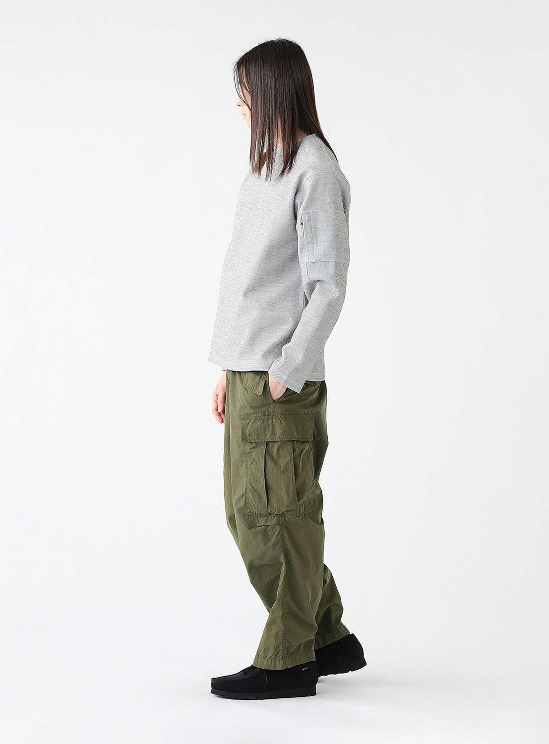 Side view of a model wearing a pair of olive green cargo pants with multiple pockets, styled.