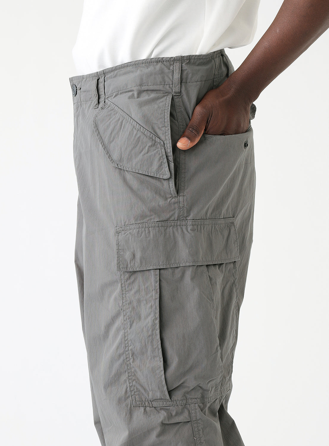 Close up view of model wearing a pair of gray cargo pants highlighting the multiple pocket details.