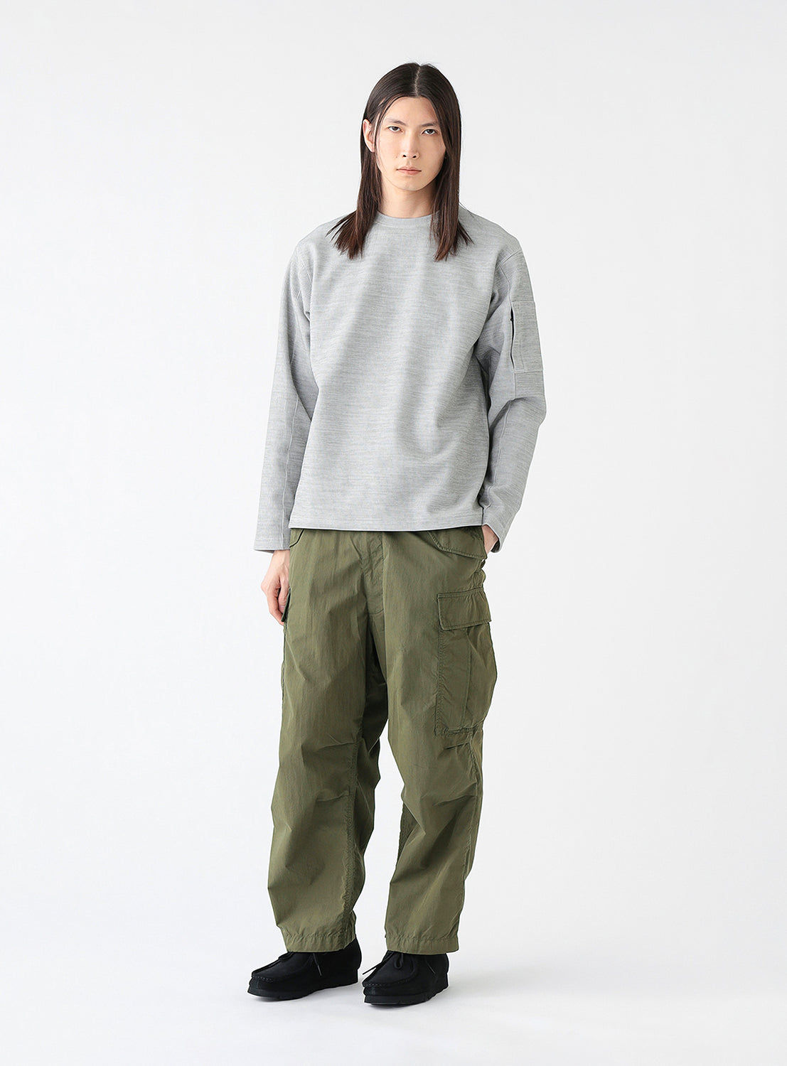 A model wearing a pair of olive green cargo pants with multiple pockets, styled.