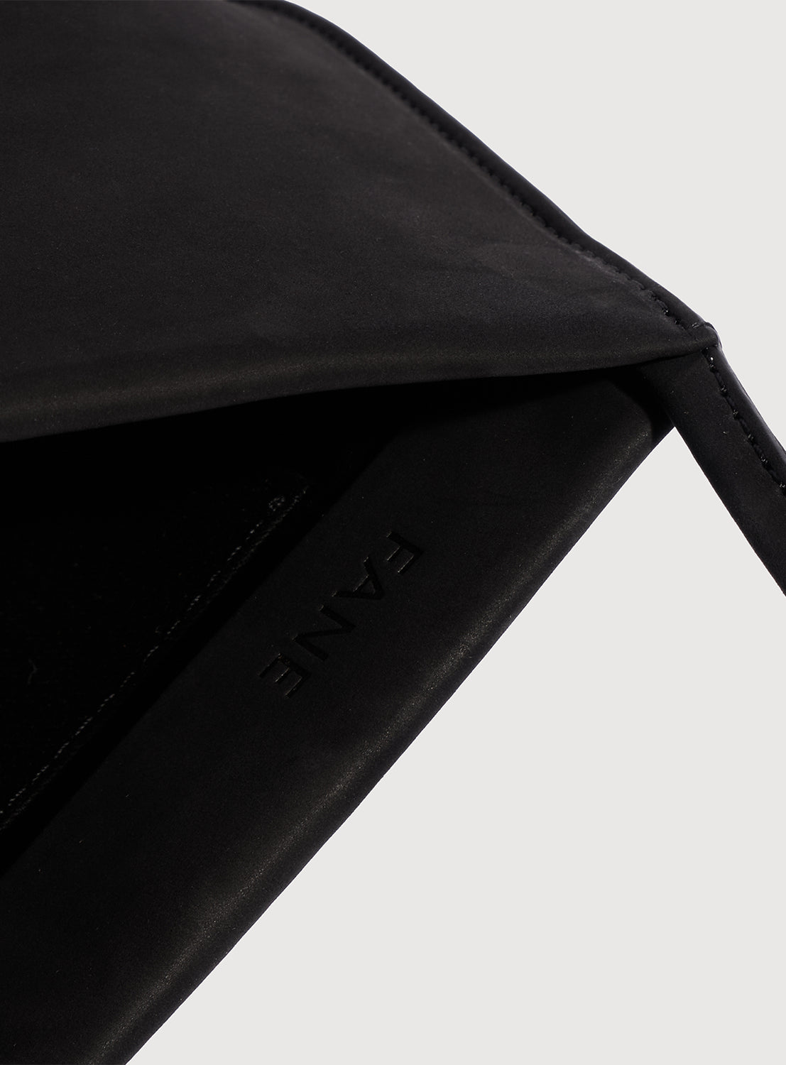 Close-up of a black leather shoulder bag with 'FANE' branding imprinted on the inside.
