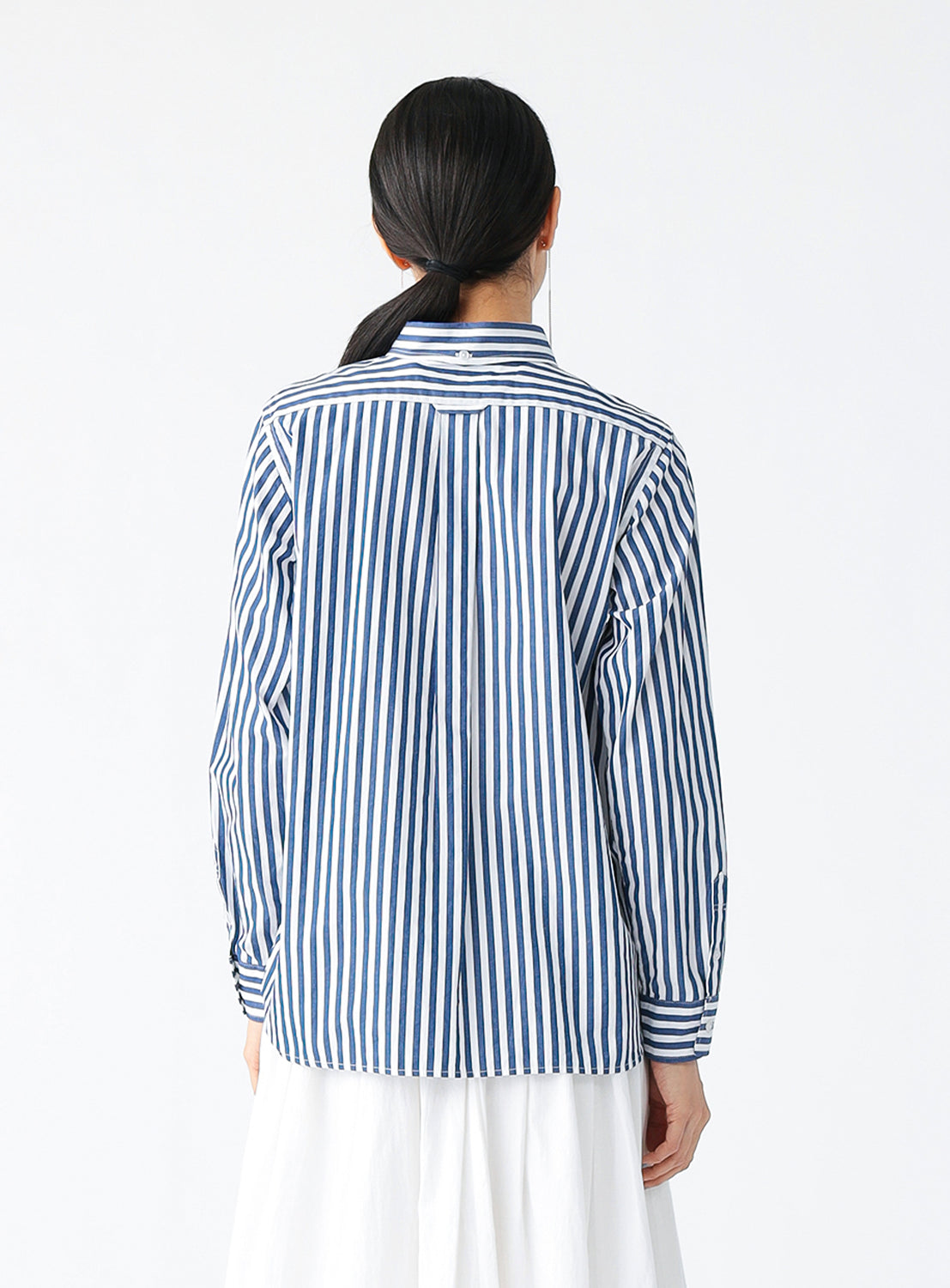 Backside view of a model wearing a blue and white striped button-down shirt for women.