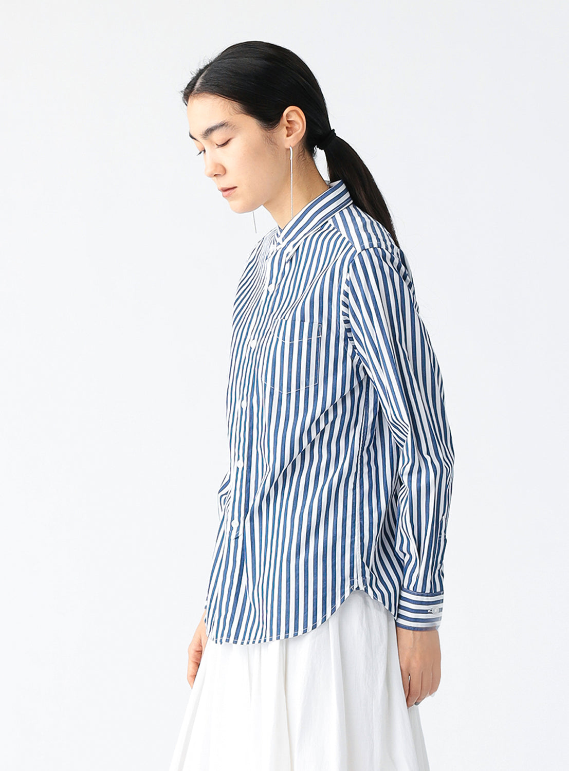 Side view of a model wearing a blue and white striped button-down shirt for women.