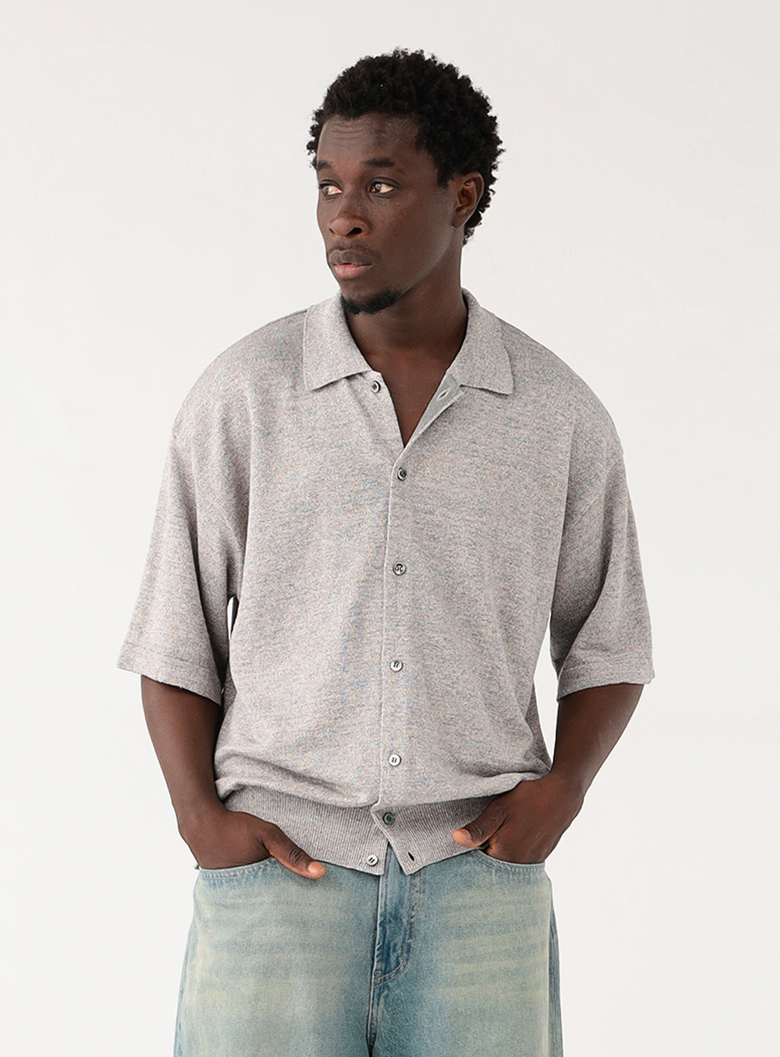 Male model wearing a light grey, short-sleeved collared shirt, looking forward.