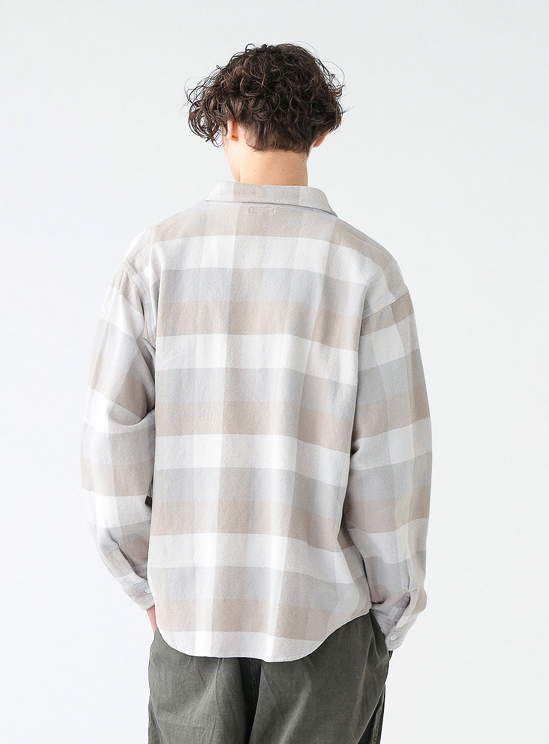 Back of model wearing a beige and white check flannel shirt with long sleeves.