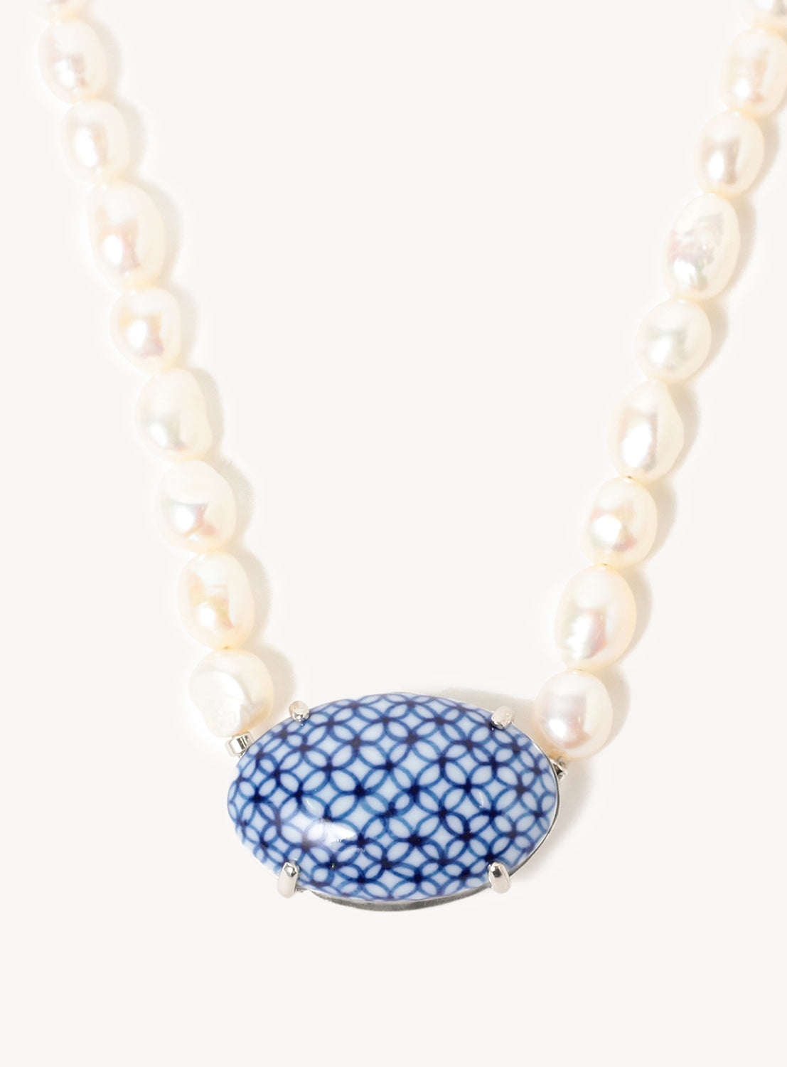 Close up of the pearl chain and oval blue motif with an intricate design.