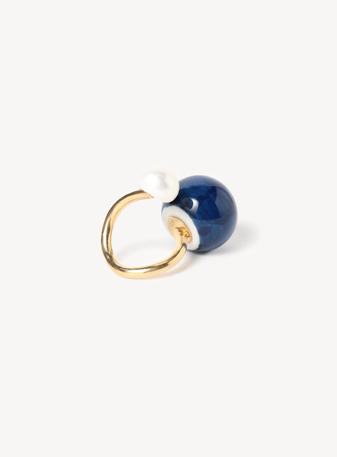 Back view of a ring with a solid blue motif and a white pearl motif, with a gold band.
