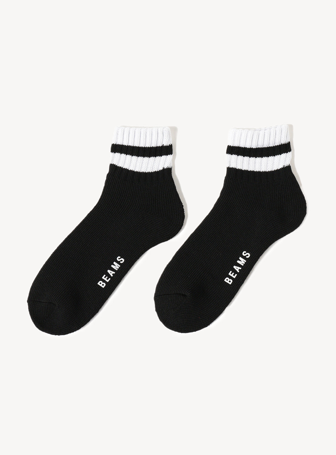 A pair of black socks with white stripes and 'BEAMS' text in white.