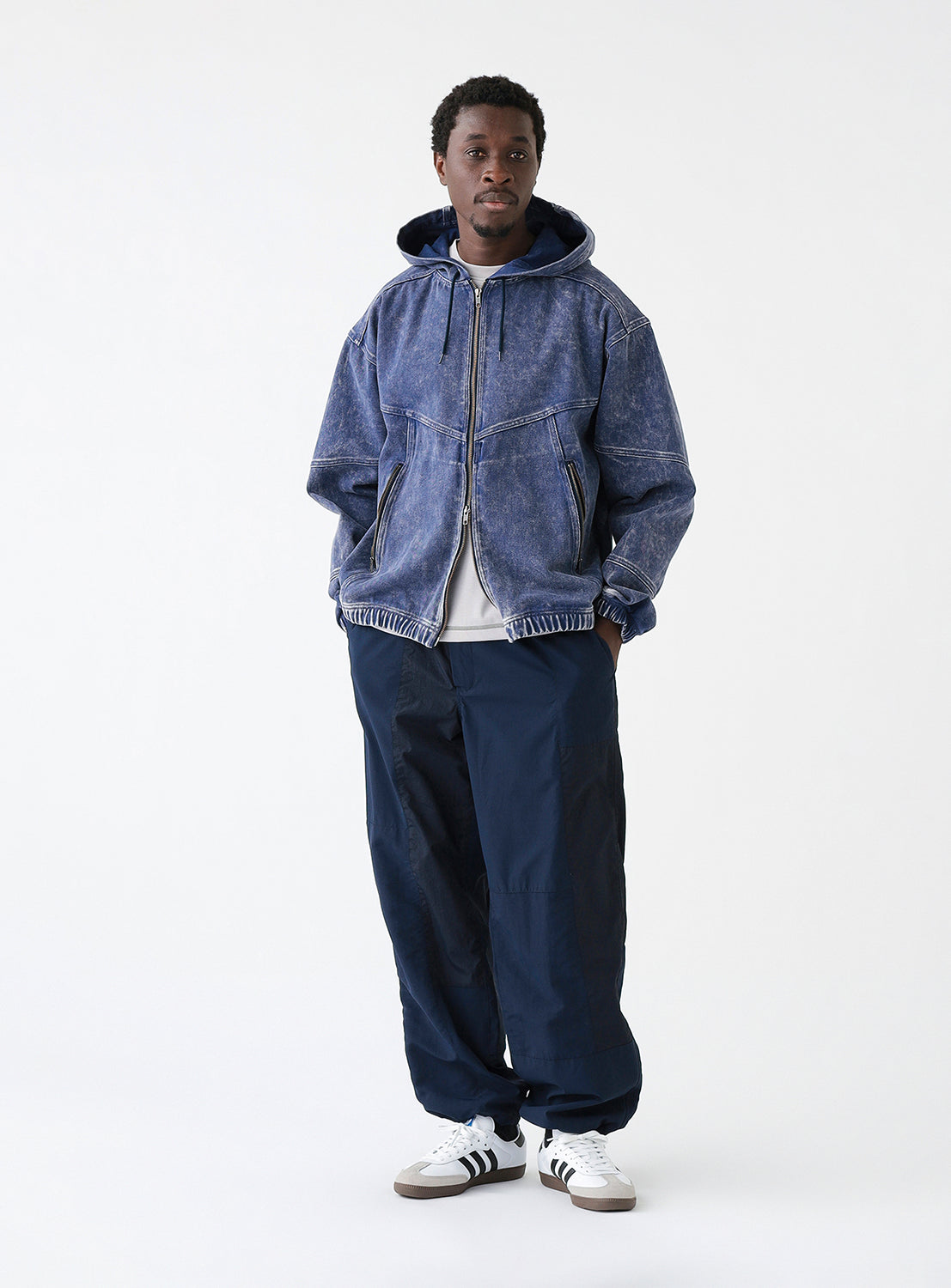 A model wearing a pair of navy blue track pants, styled.