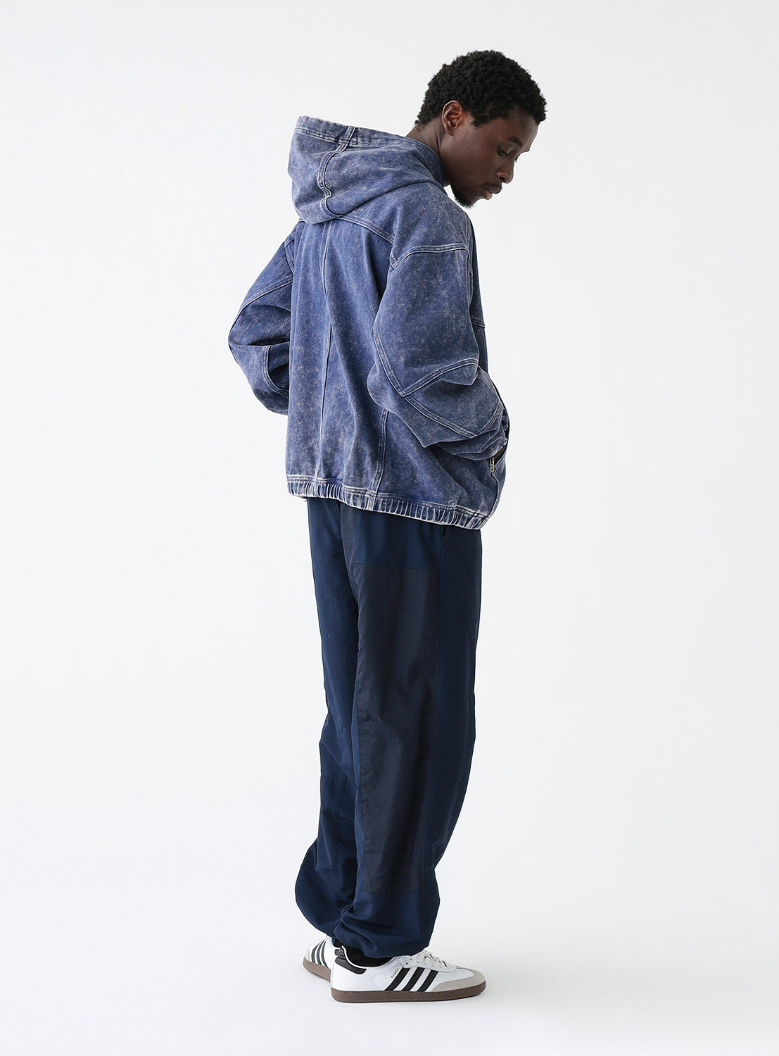 Side view of a model wearing a pair of navy blue track pants, styled.