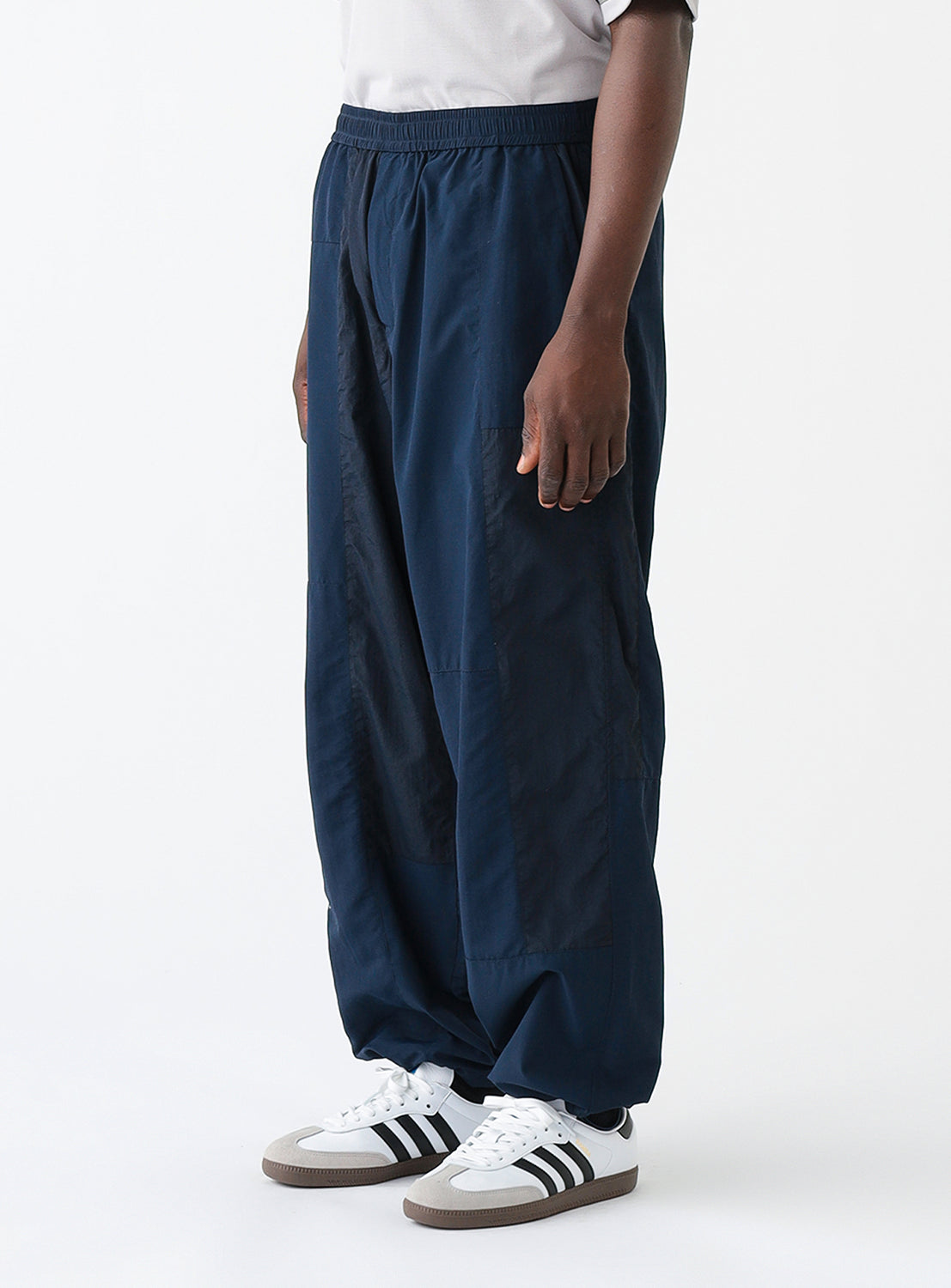 Close up quarter view of a model wearing a pair of navy blue track pants.