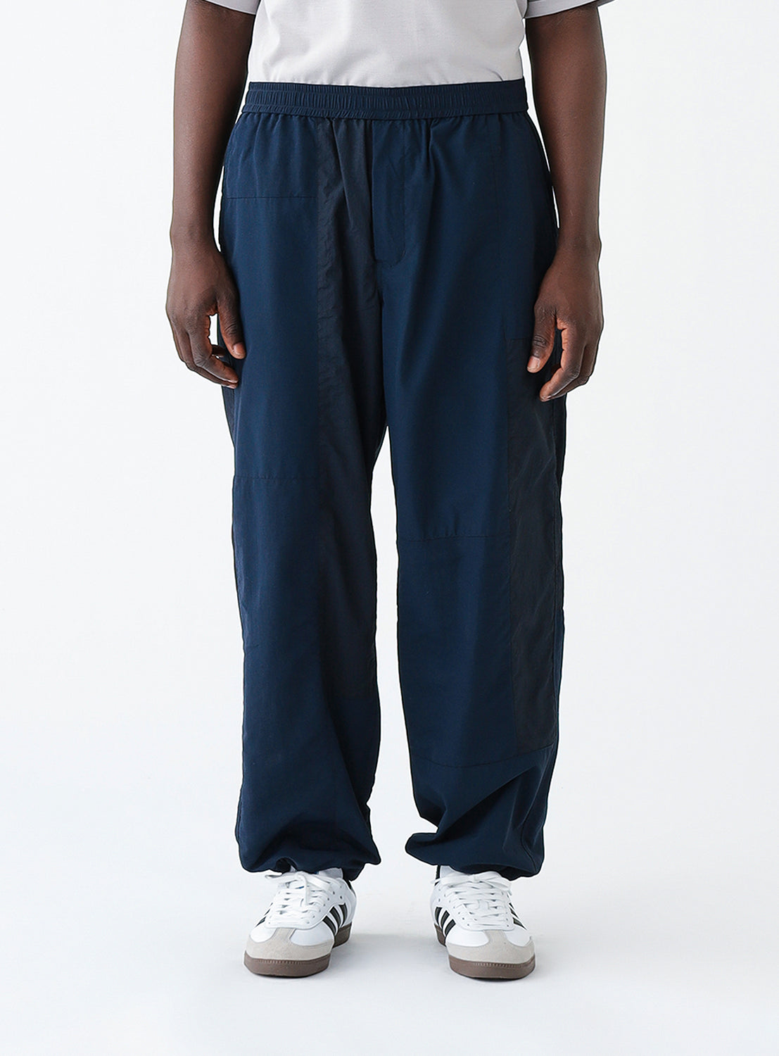 Close up front view of a model wearing a pair of navy blue track pants.