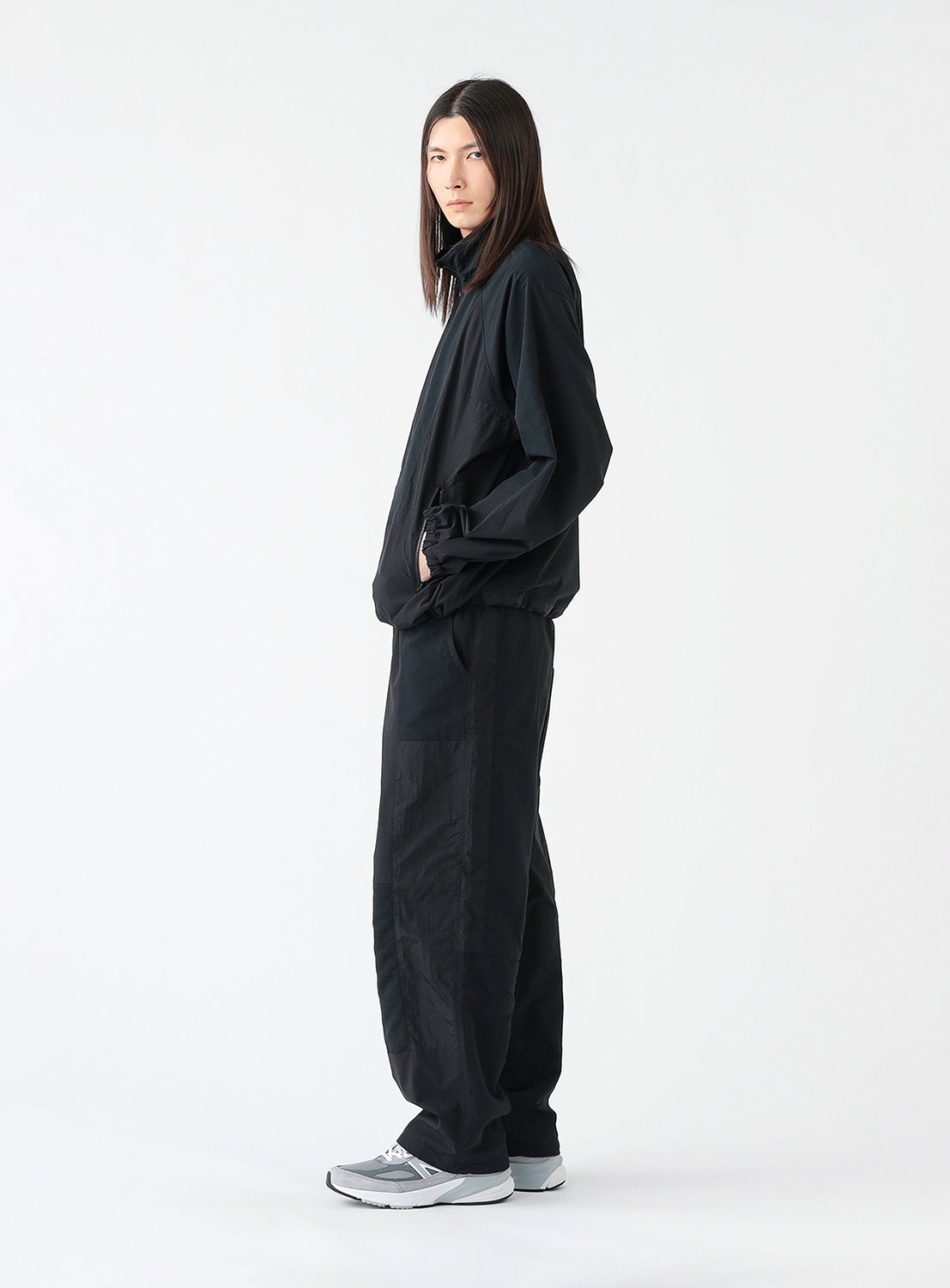 Side view of a model wearing a pair of black track pants, styled.