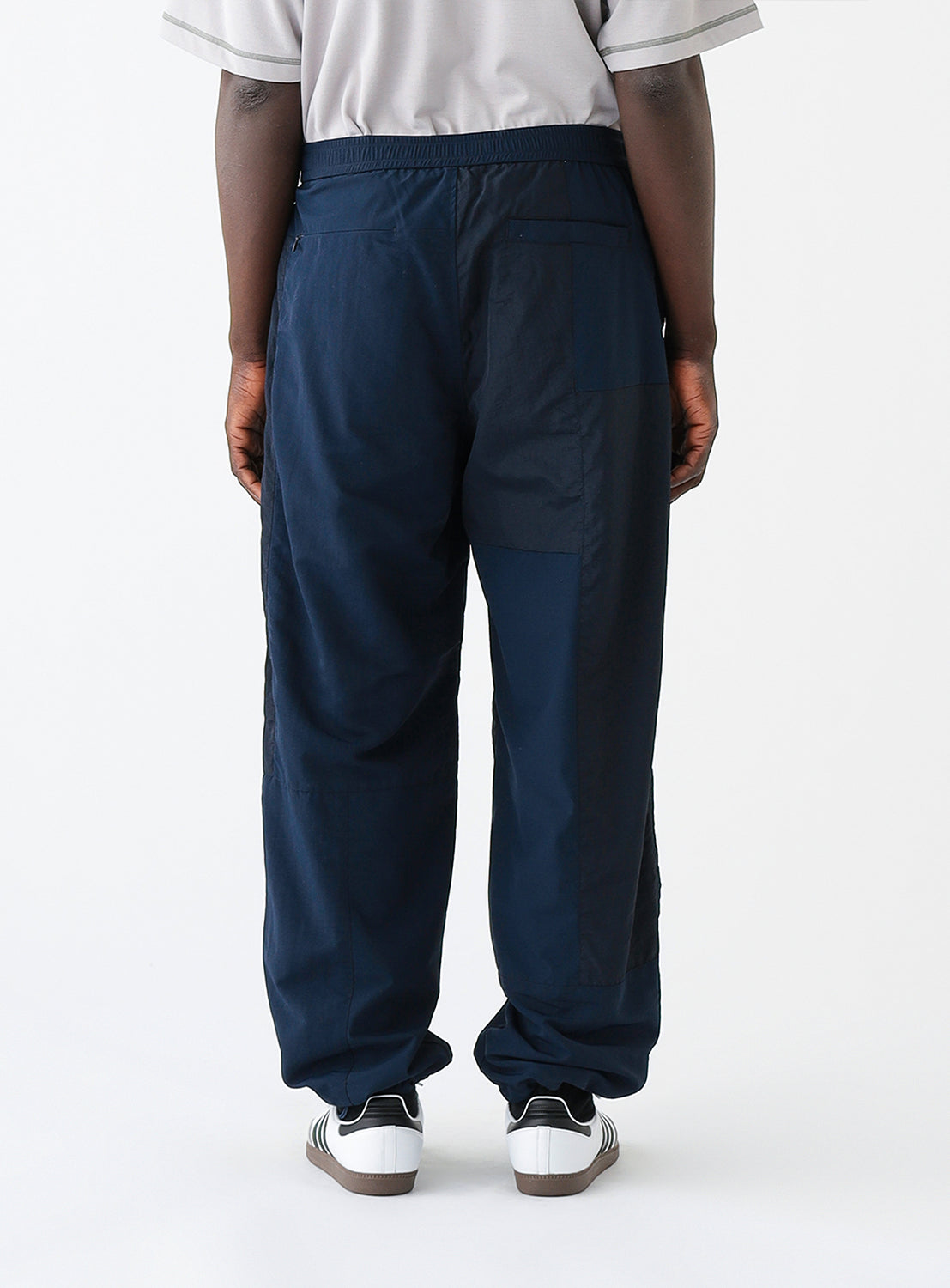 Close up back view of a model wearing a pair of navy blue track pants.