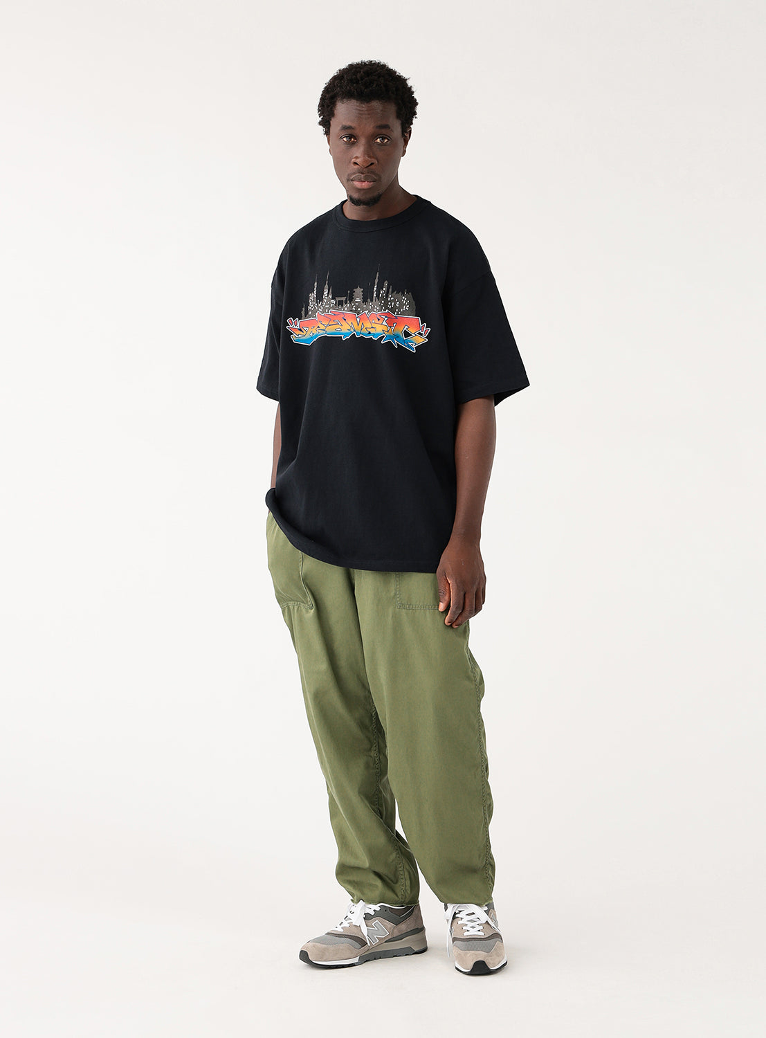 Front view of a model wearing olive green loose-fit cargo pants with a black t-shirt, displaying the comfortable fit.