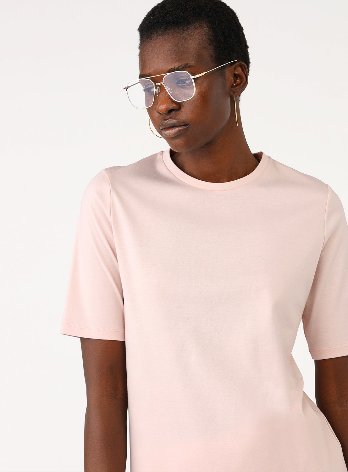 Model showcasing the fit of the light pink short-sleeve shirt from the front.