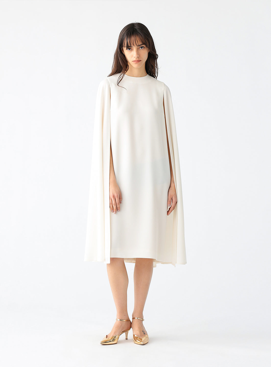 Model wearing a cream cape dress.