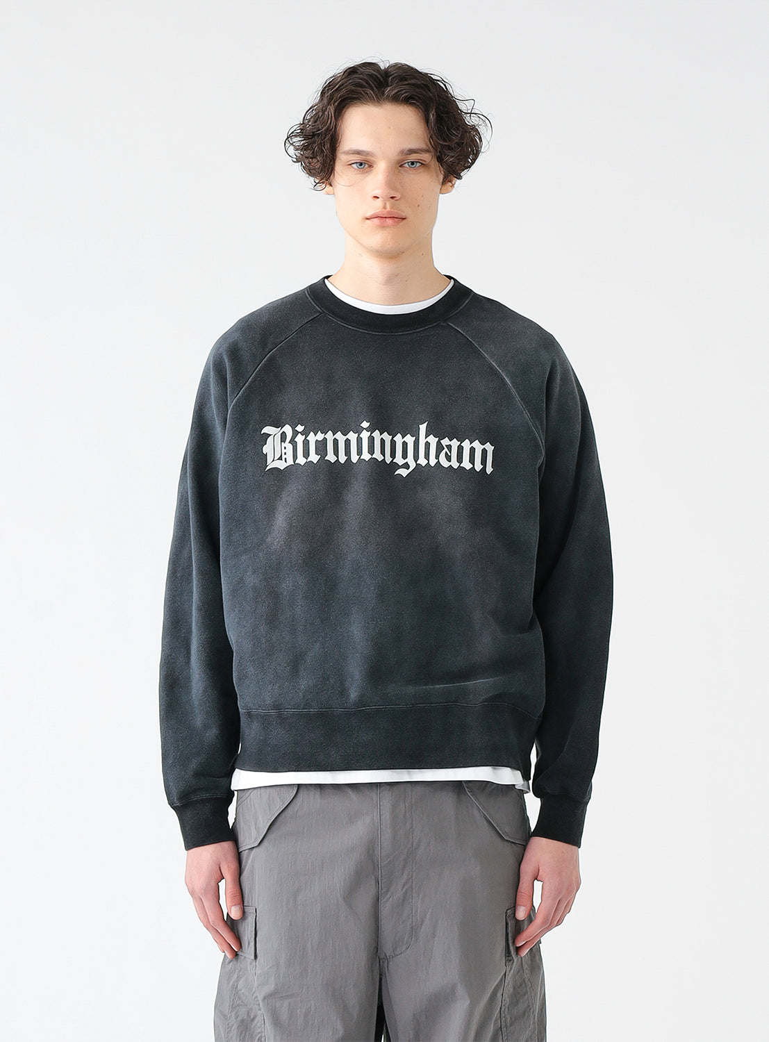 Model wearing a black faded crewneck sweatshirt with the text 'Birmingham' printed in white on the front.