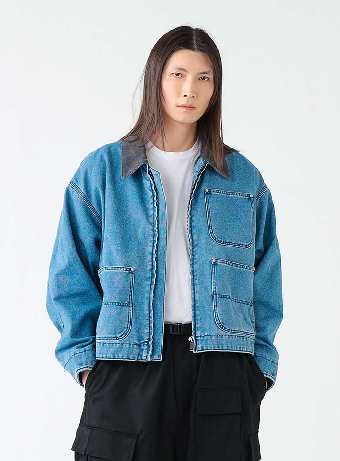 Model wearing a faded blue denim blouson jacket with a dark collar, multiple pockets, and a zip-up front.