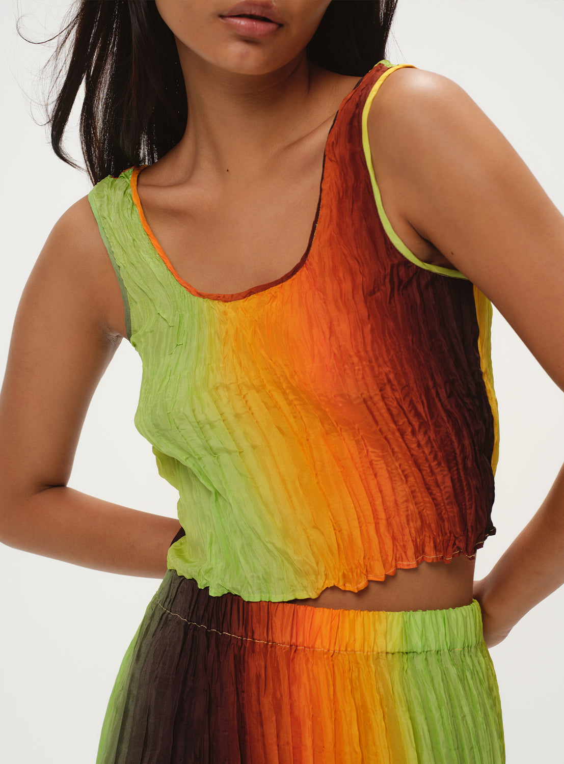 Close-up of a model wearing a green, yellow, and orange ombre knit top and a matching skirt.