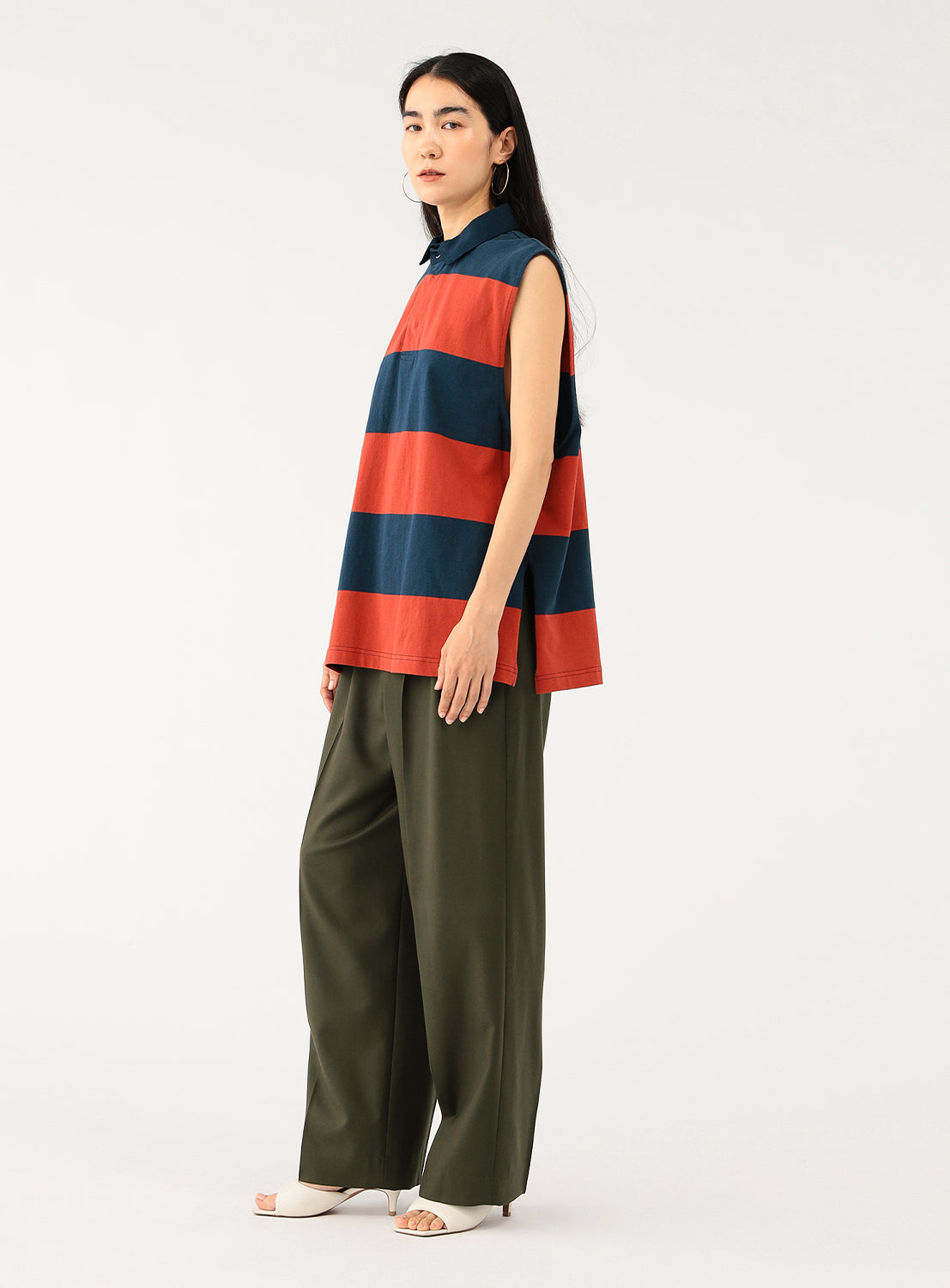 Model showcasing a styled outfit, featuring khaki pleated trousers paired with a colorful top.
