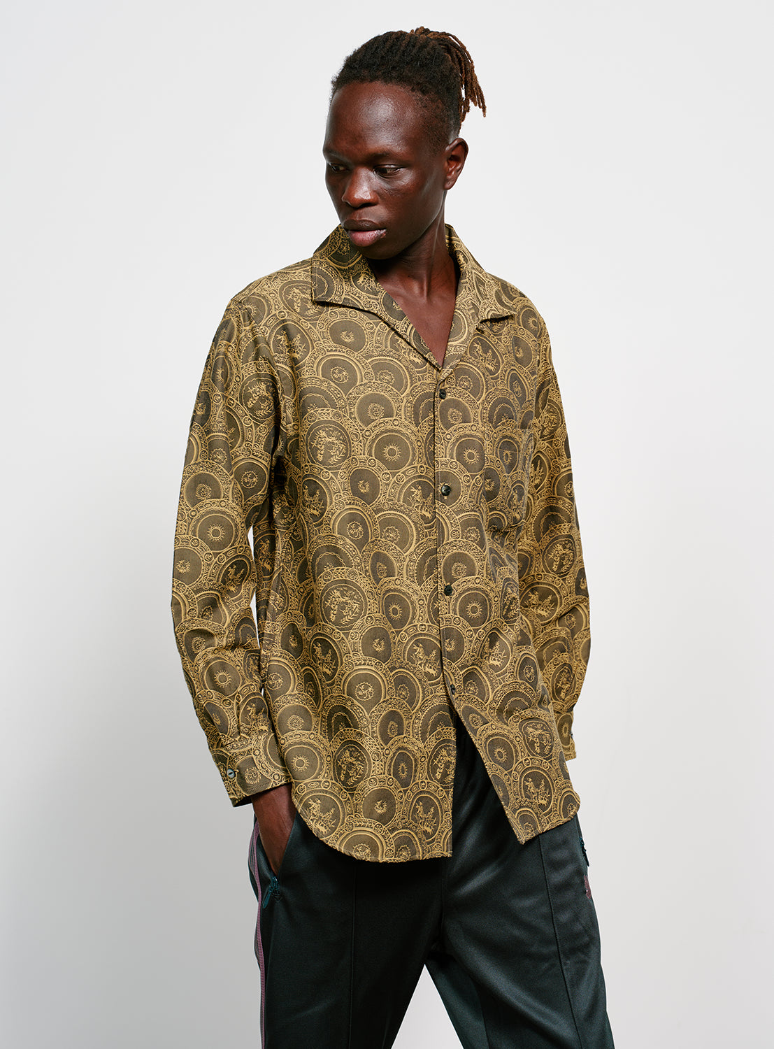 Model wearing a brown and yellow Italian patterned, collared button down shirt.