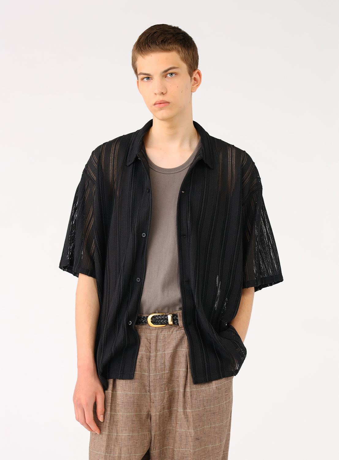Front view of a model in a black polyester mesh shirt, layered over a tee.