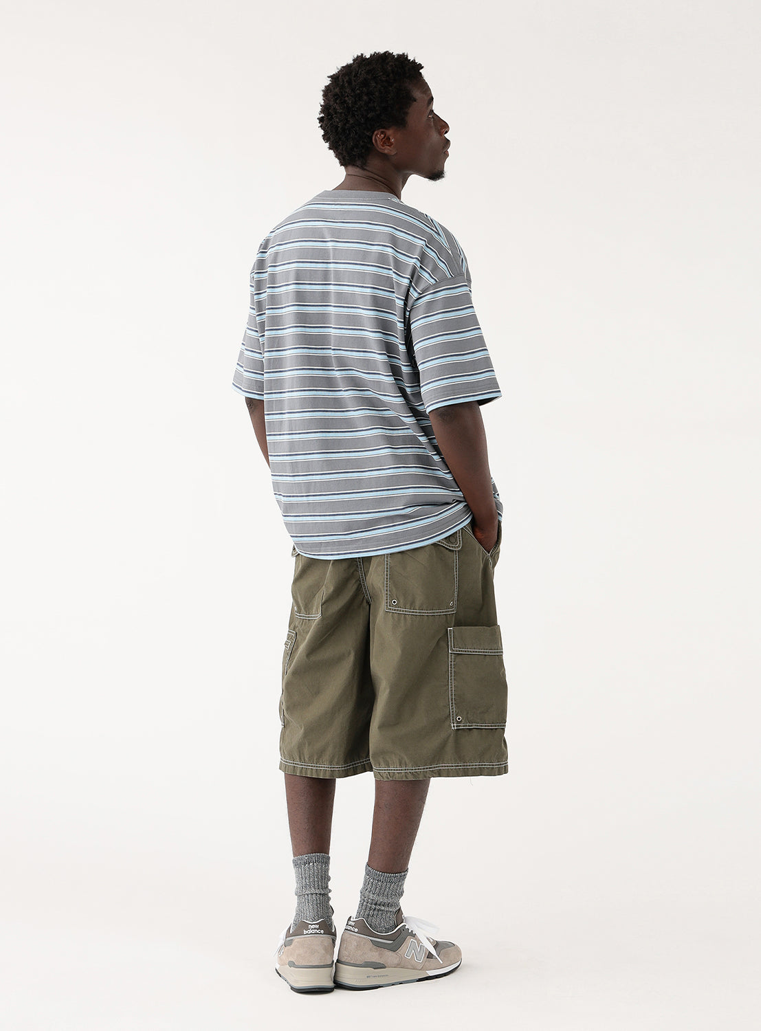 Back view of a model in the grey striped t-shirt, showcasing the relaxed fit from behind.