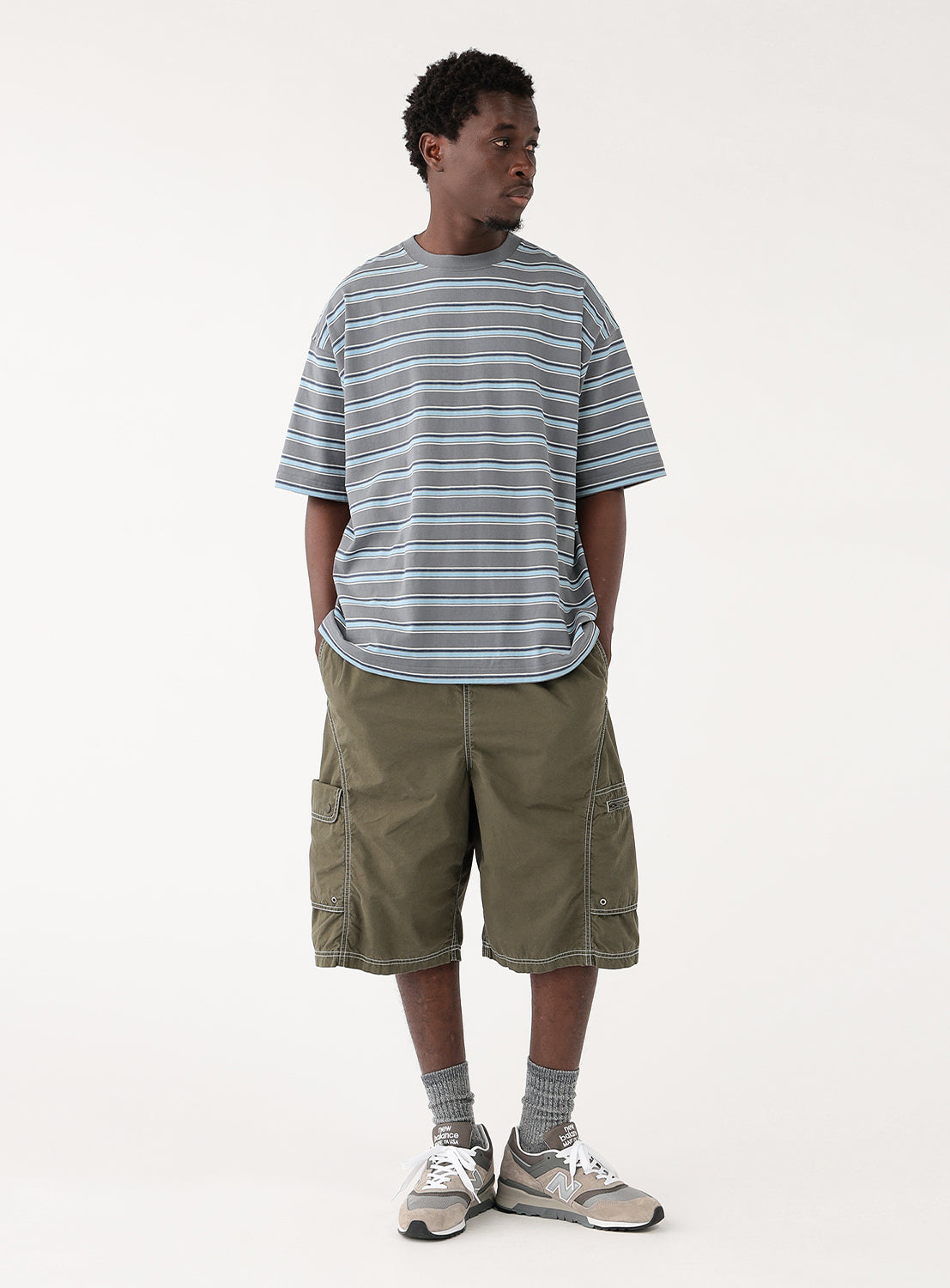 model in the grey striped t-shirt, showing the loose fit and length over shorts.