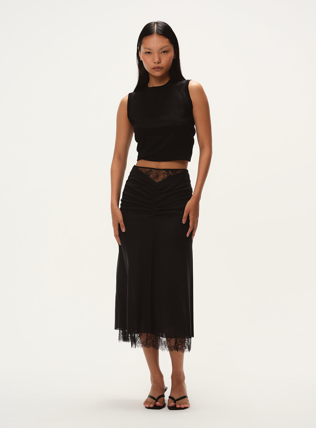 Model wearing a black skirt with black lace hem detail.