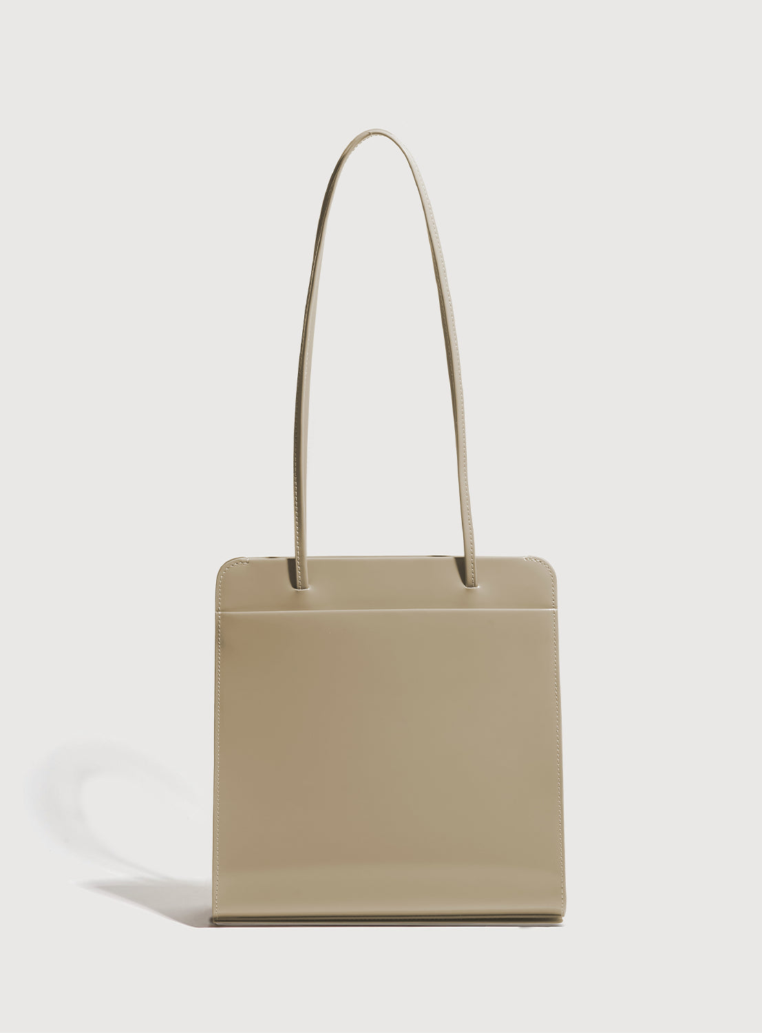 Back of latte brown square handbag with long, ribbon-like straps.