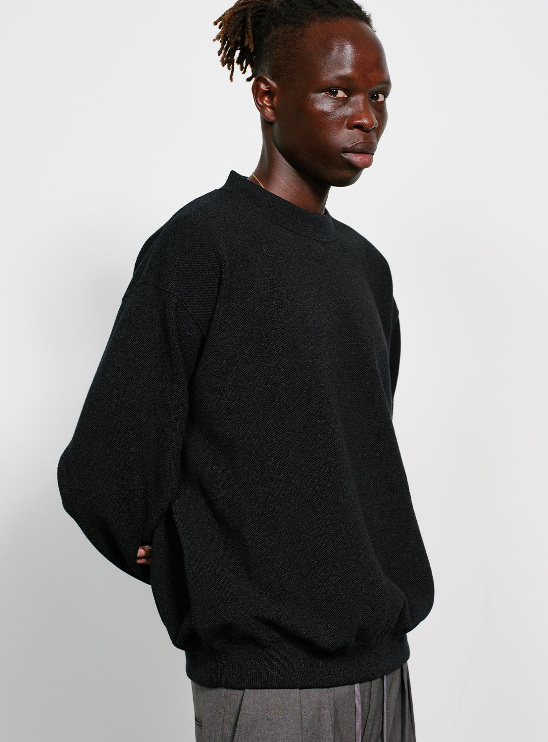 Model wearing a black crew neck sweater.
