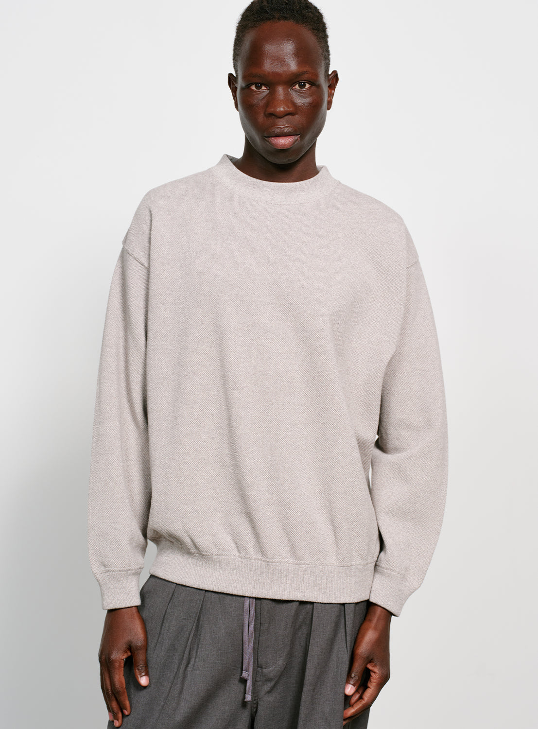 Model wearing a grey crew neck sweater.