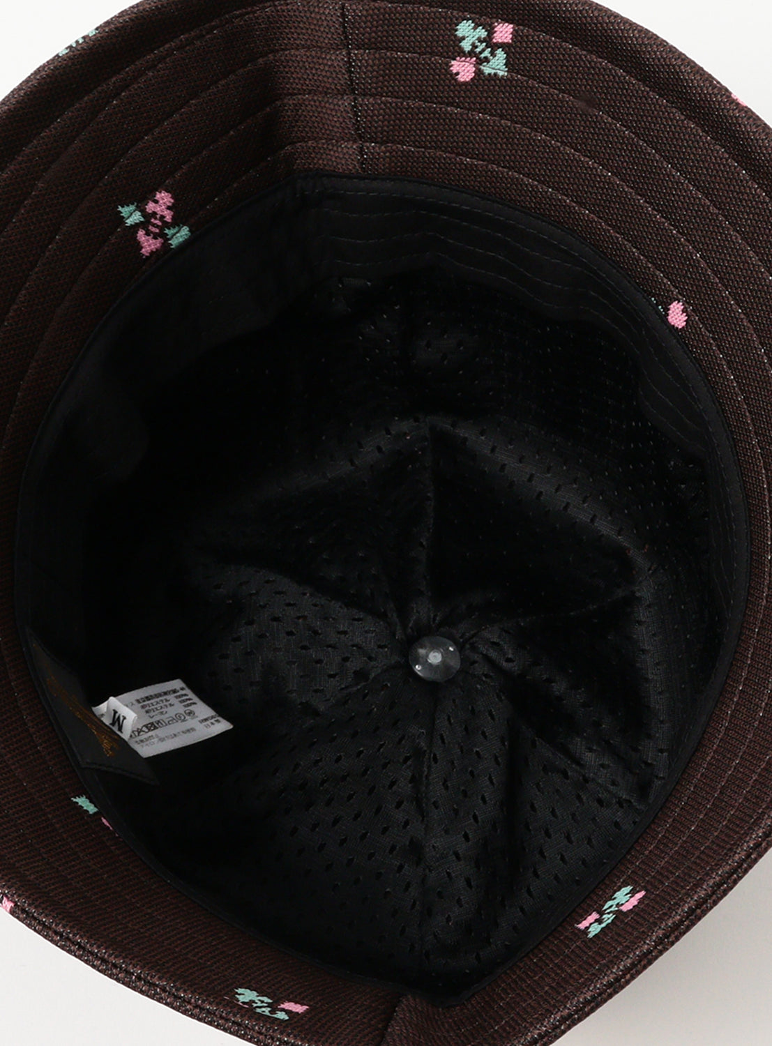 Inside of brown bucket hat with pink and mint designs and a mesh inside.