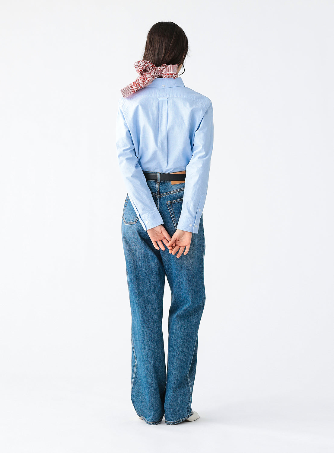 Back view of a model wearing a blue button down shirt.