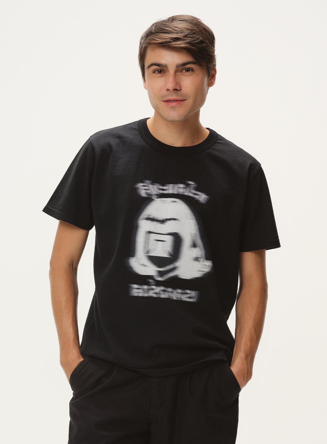 Model wearing a black t-shirt with a white cartoon graphic and black pants, front view, displaying the casual fit.